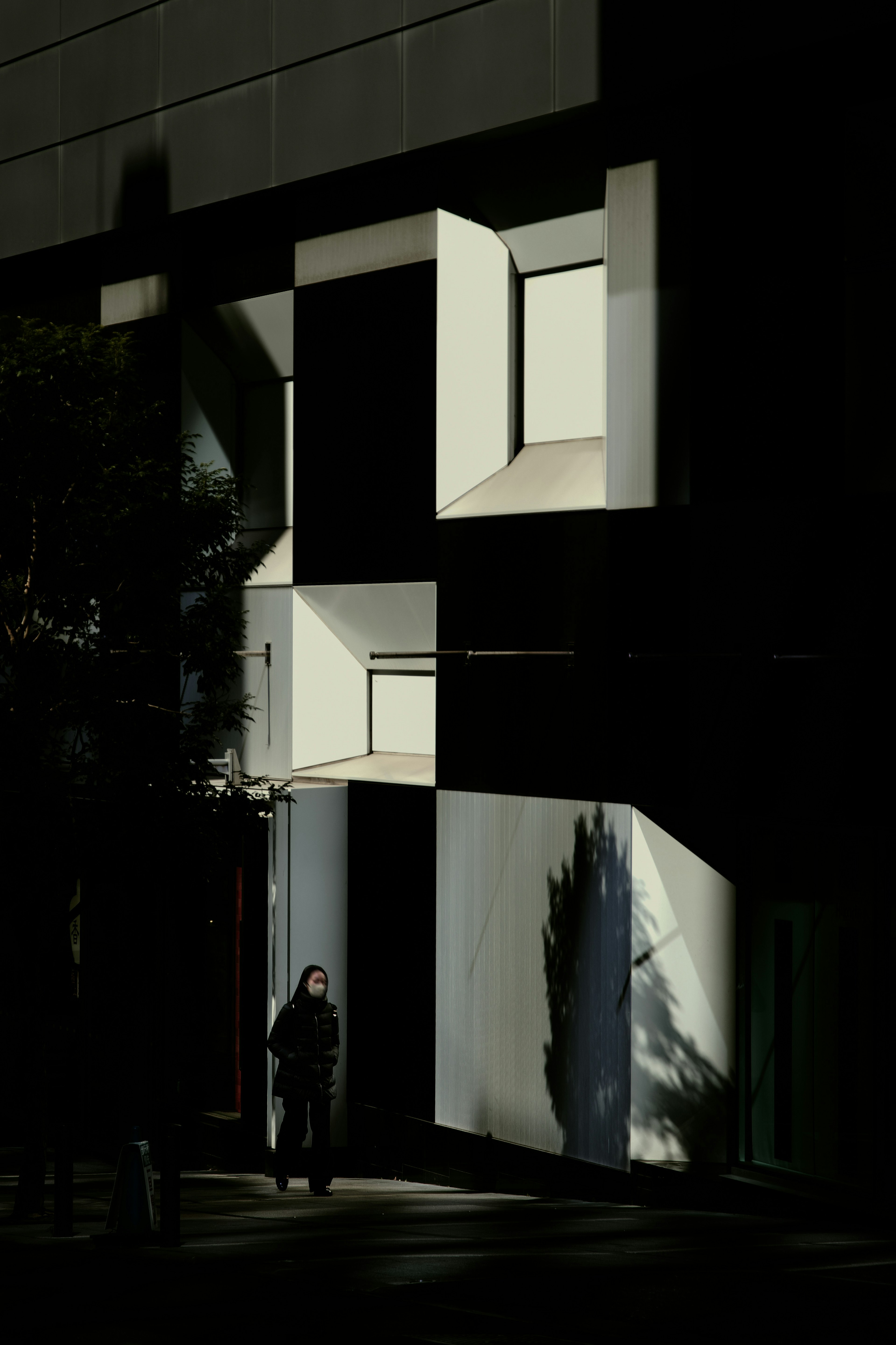 Moderne Gebäudefassade mit weißen Fenstern und Schatten vor einem dunklen Hintergrund