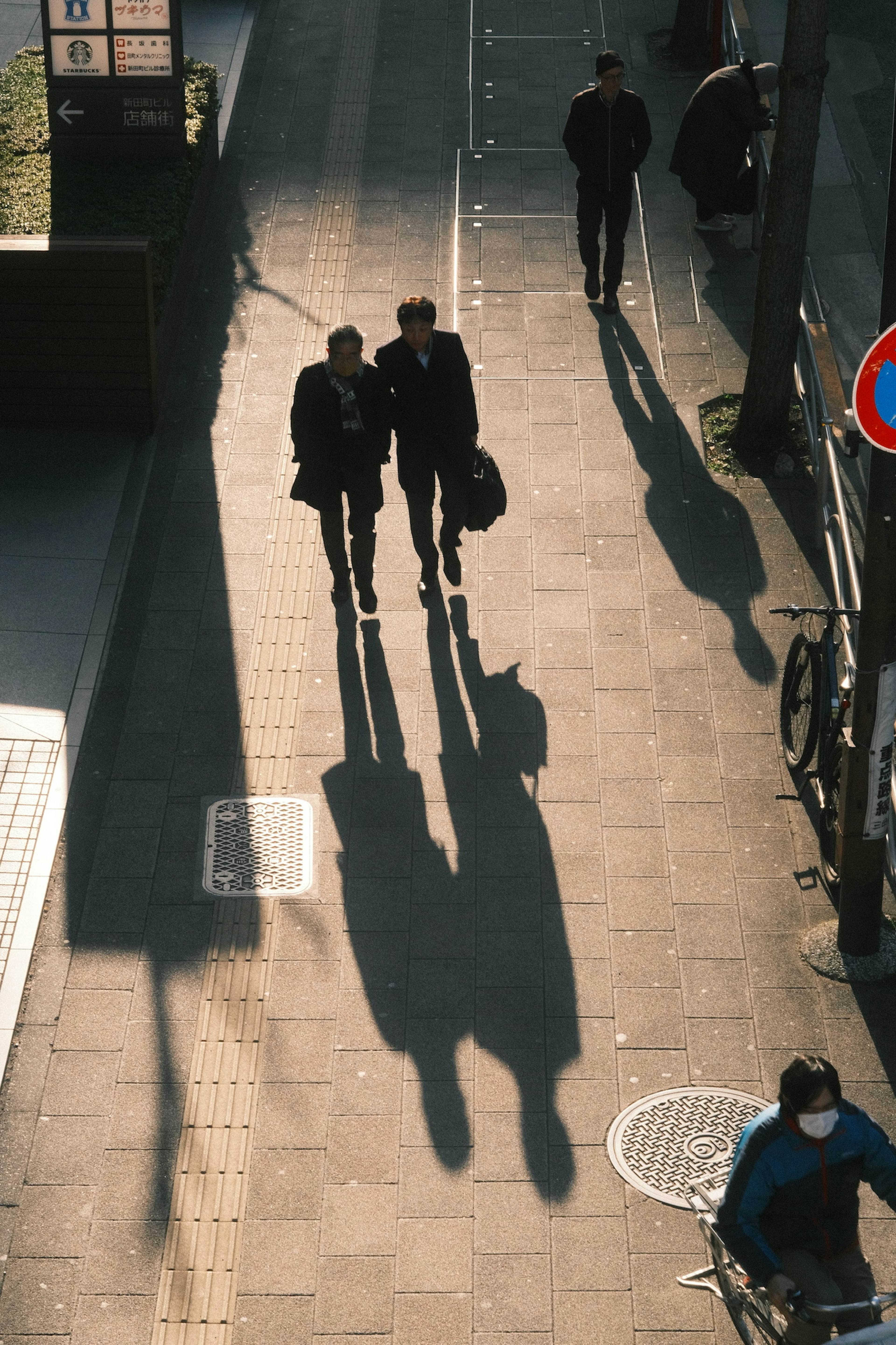 Two businessmen walking on a sidewalk with shadows cast on the ground