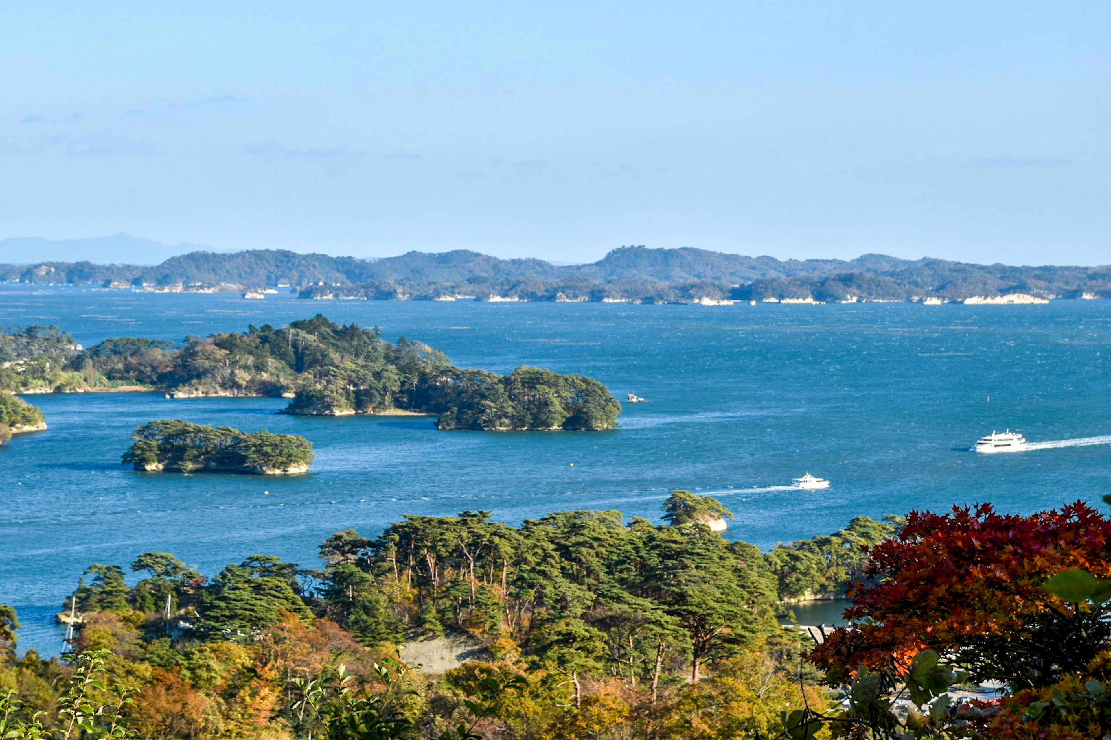 寧靜的藍色海洋與綠色島嶼和航行的船隻的景觀