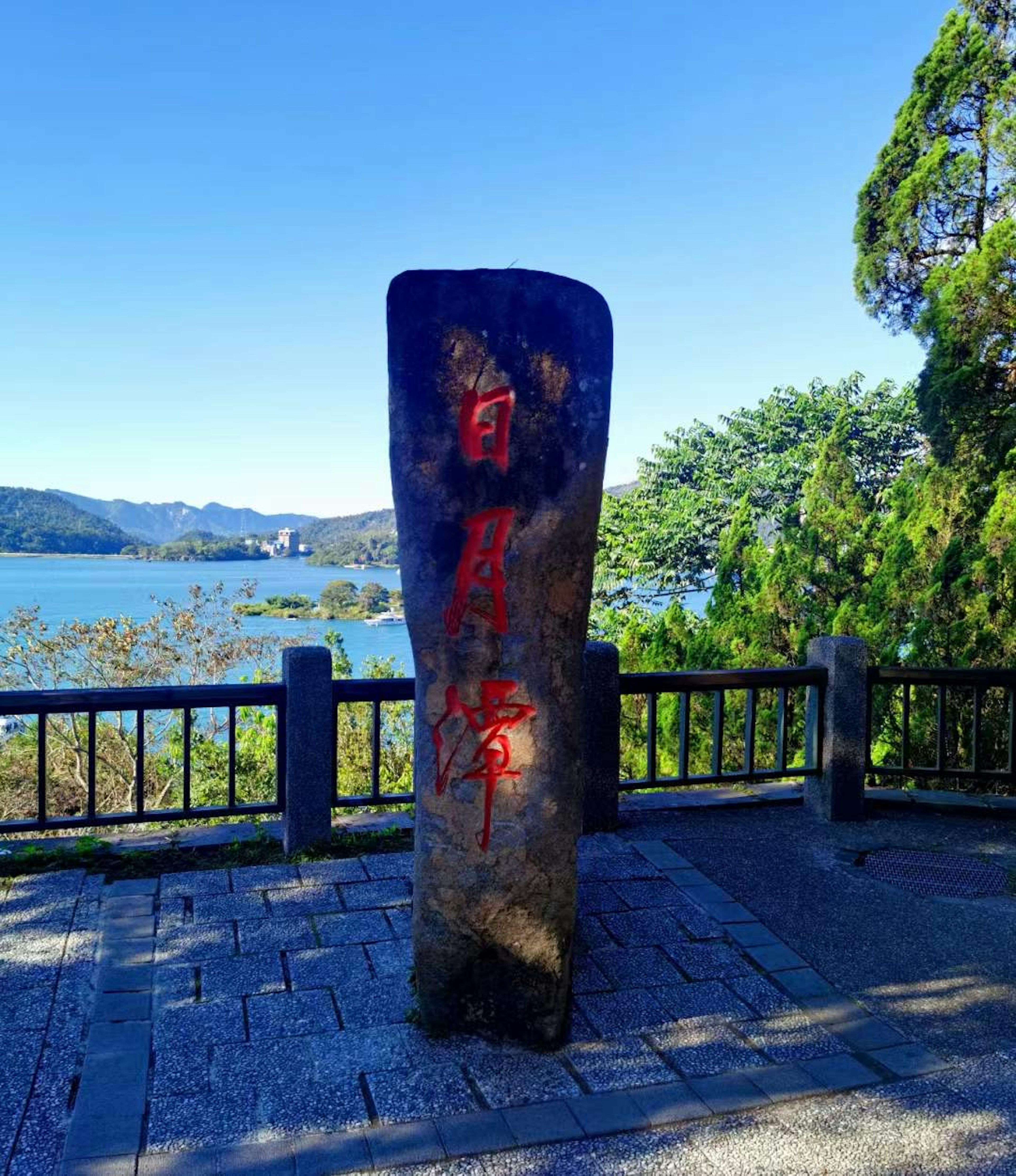 Un monument di pietra con iscrizioni rosse vicino a un lago