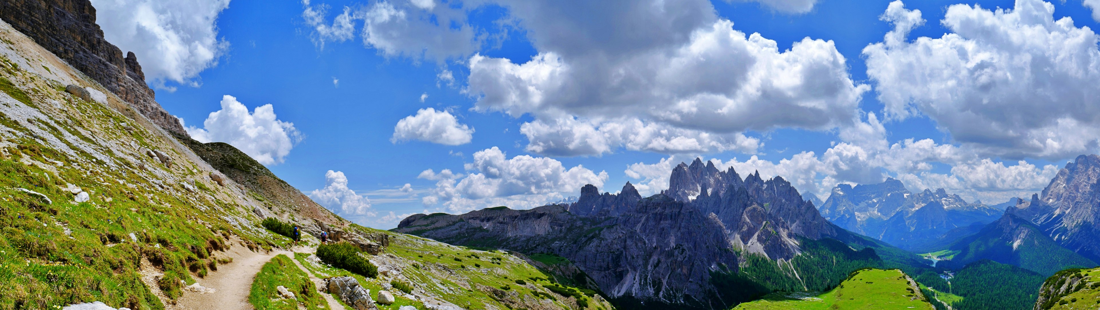 Scenic view of mountains and blue sky with a green meadow and pathway