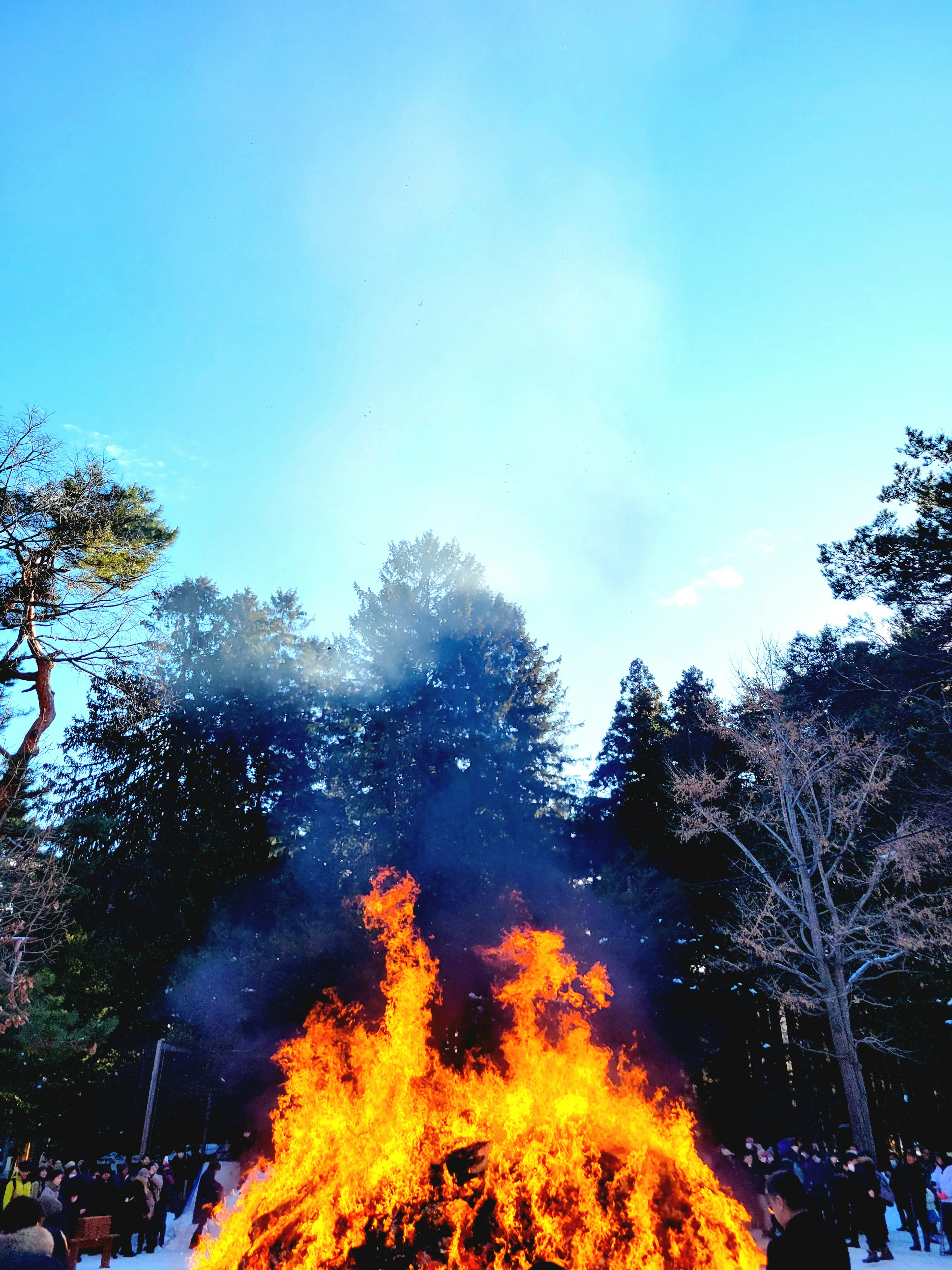 A large fire burning with smoke under a blue sky