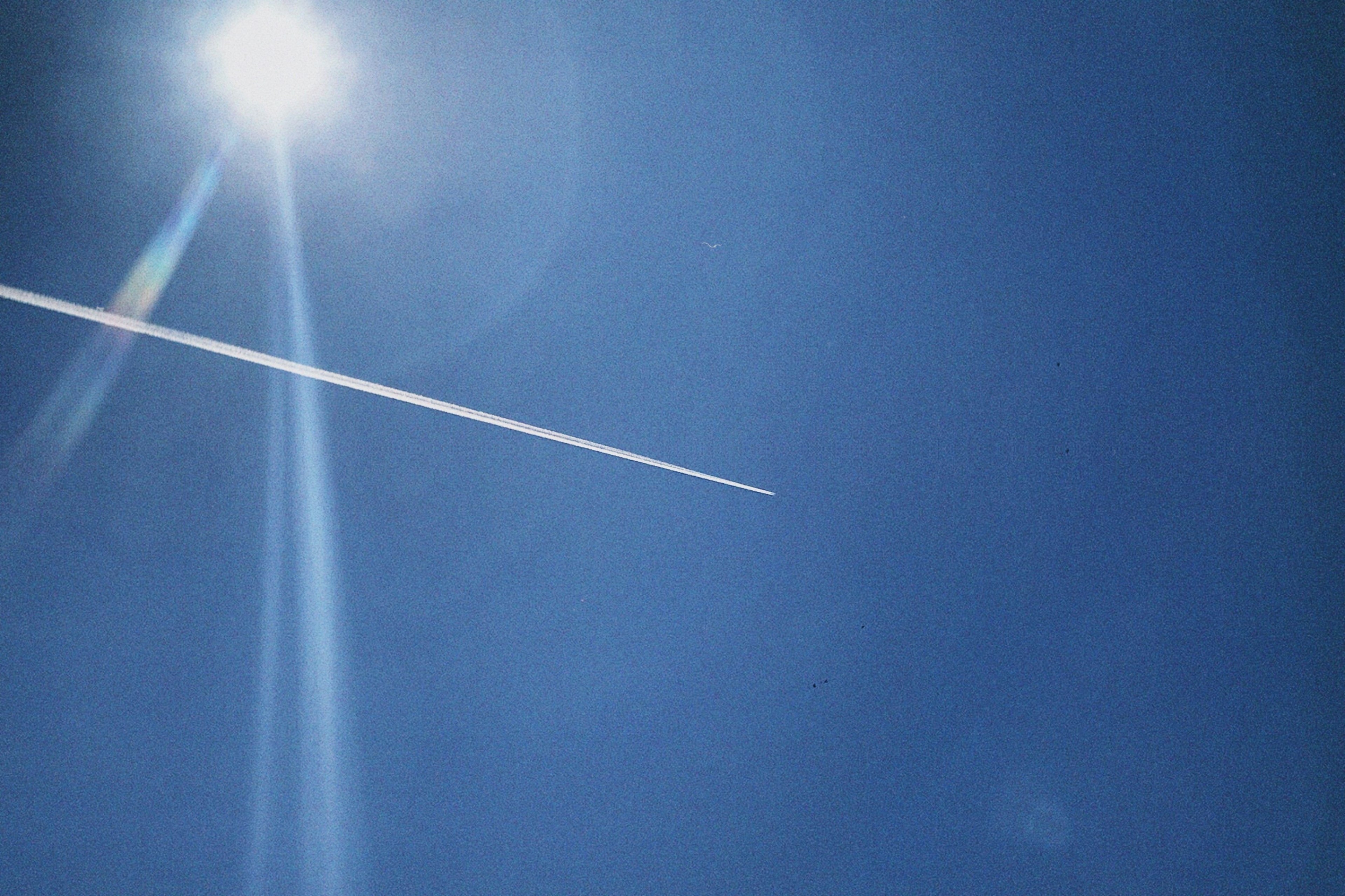 Scia di aereo nel cielo azzurro con luce solare brillante