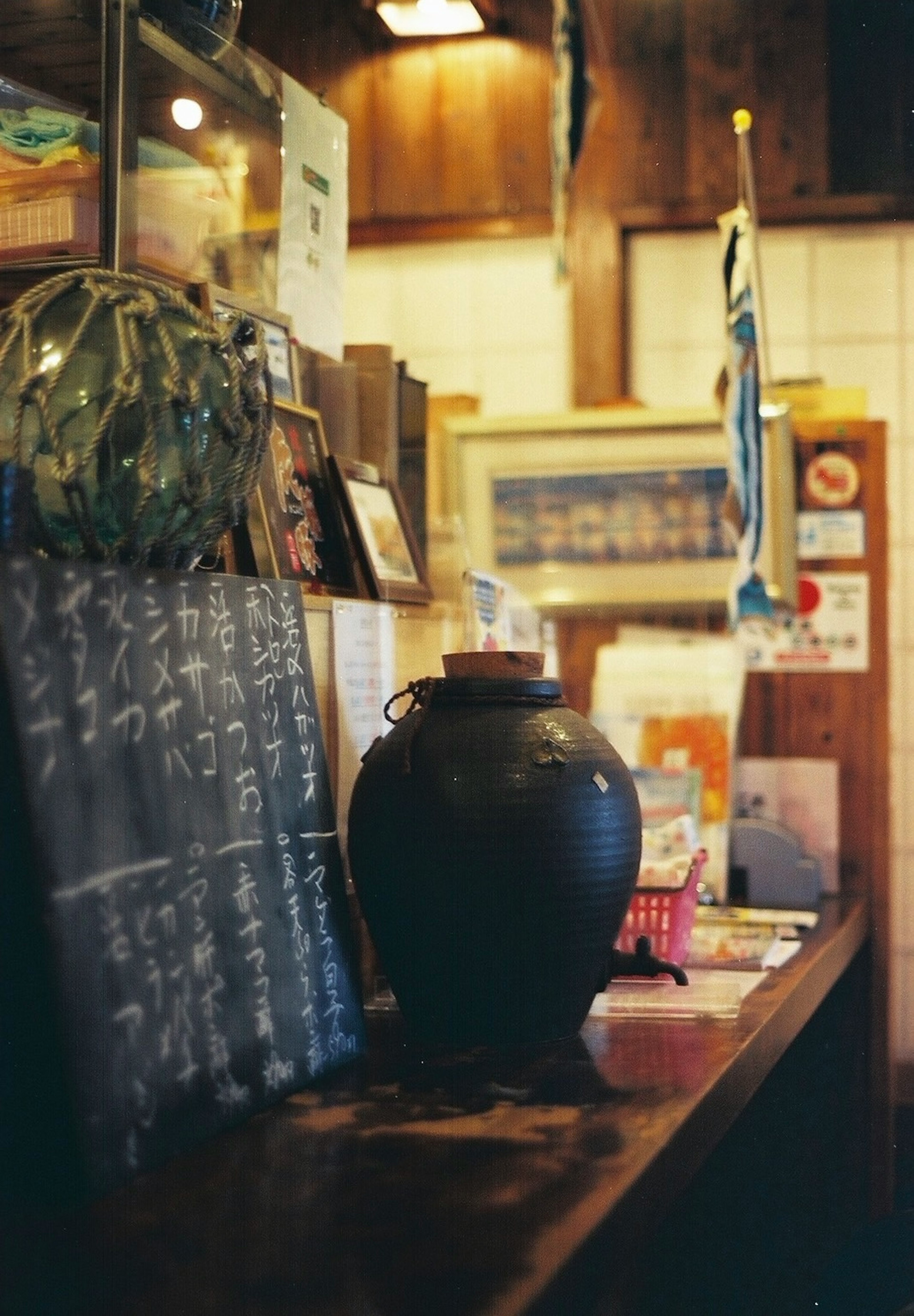 Interior izakaya dengan jar hitam di meja dan menu tulisan tangan