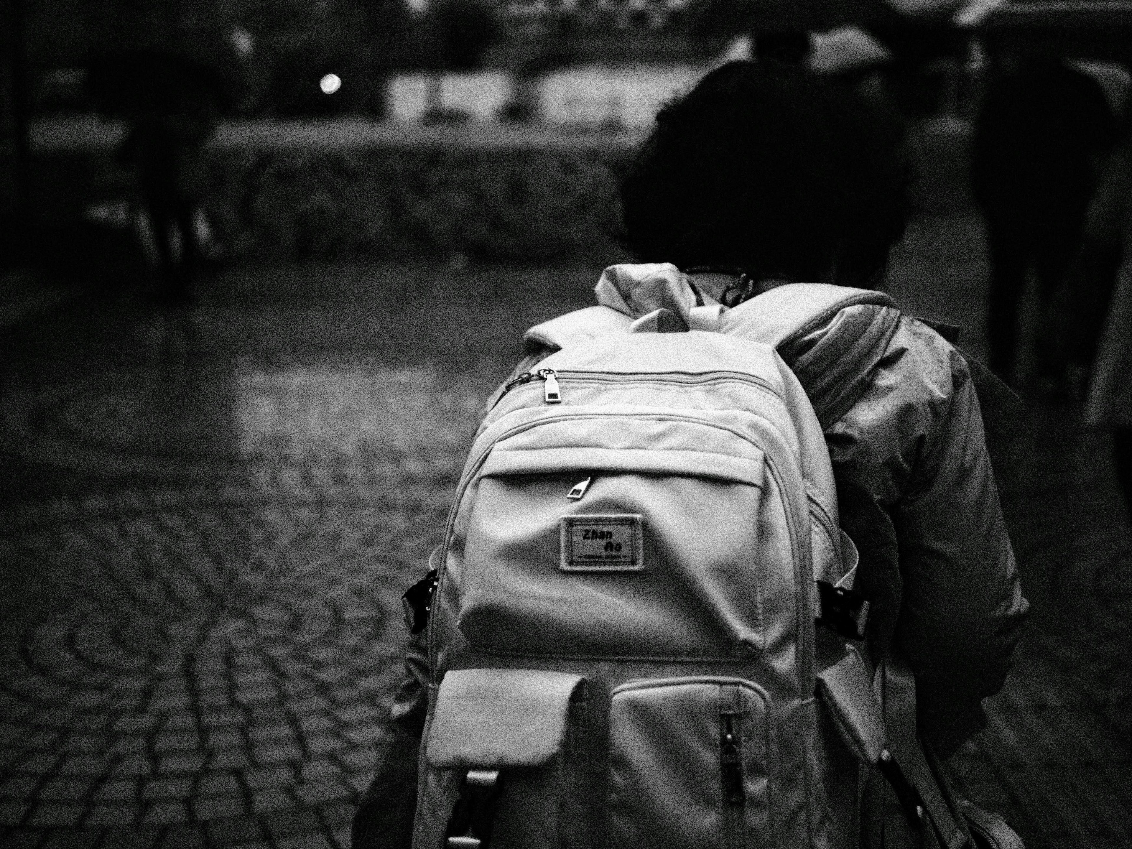 Person walking on cobblestone with white backpack