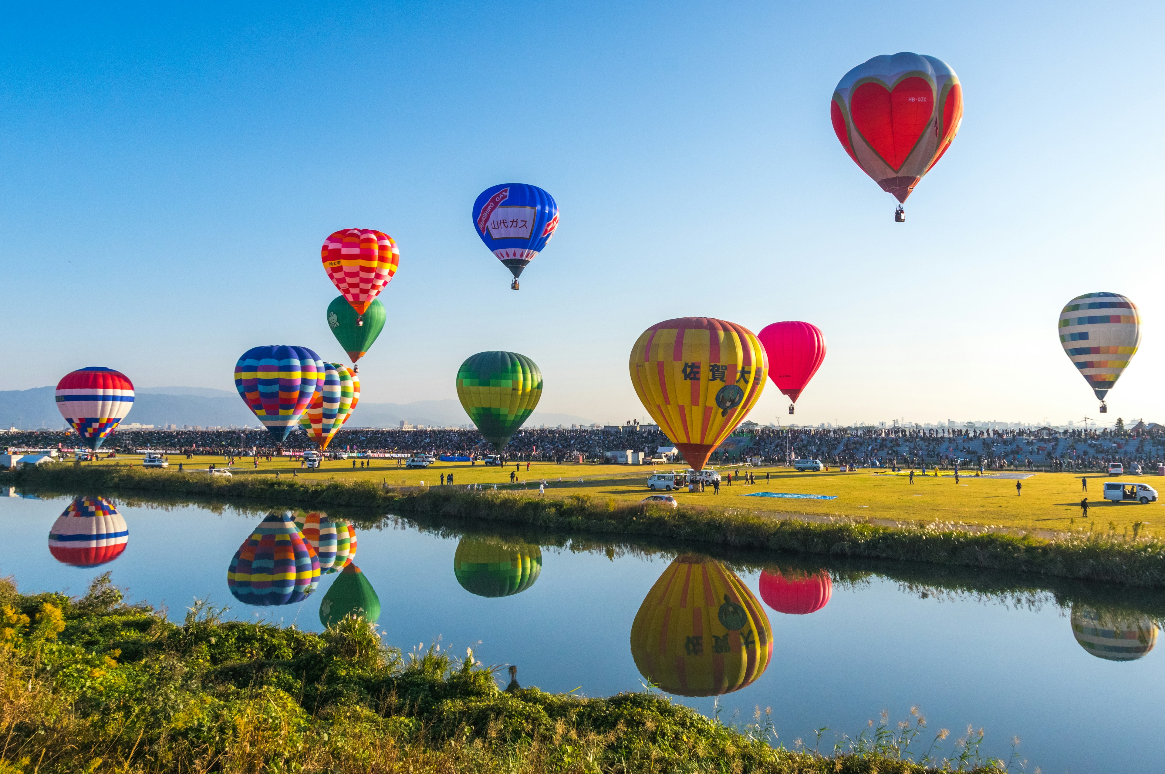 Globos aerostáticos coloridos flotando sobre un lago sereno