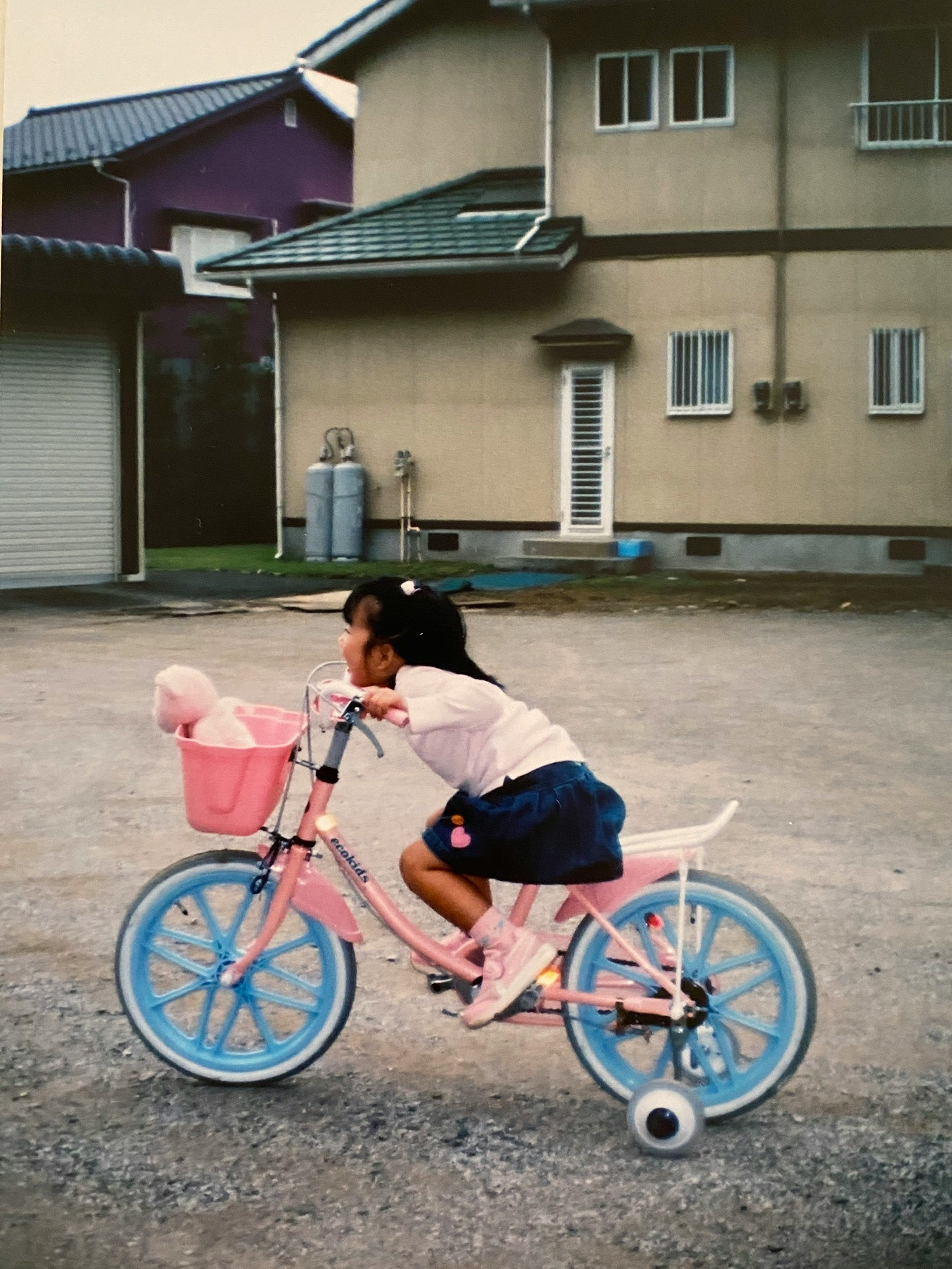 ピンクの自転車に乗る小さな女の子とそのカゴにいるぬいぐるみ