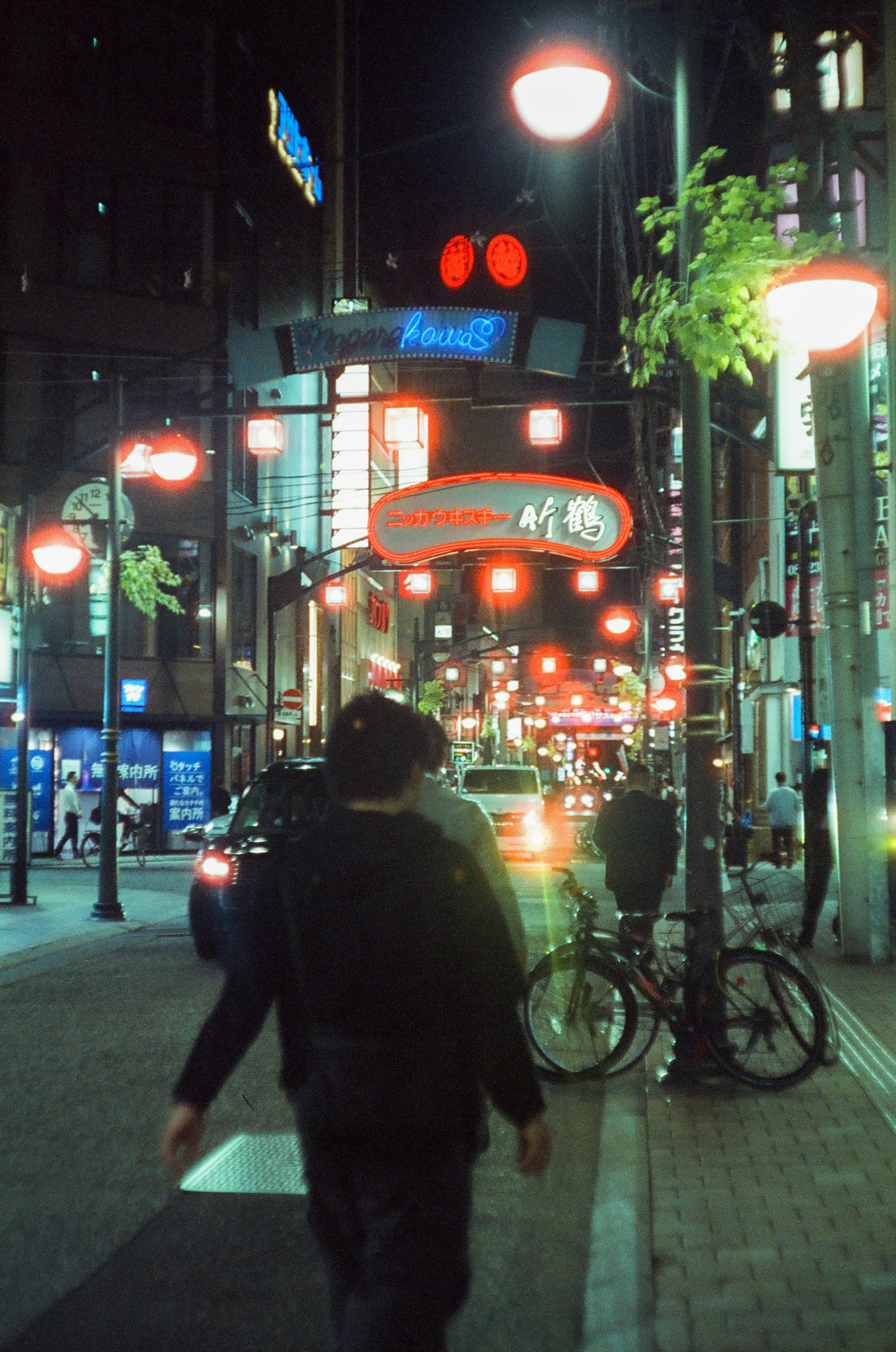 Person walking through a vibrant city street at night with bright streetlights