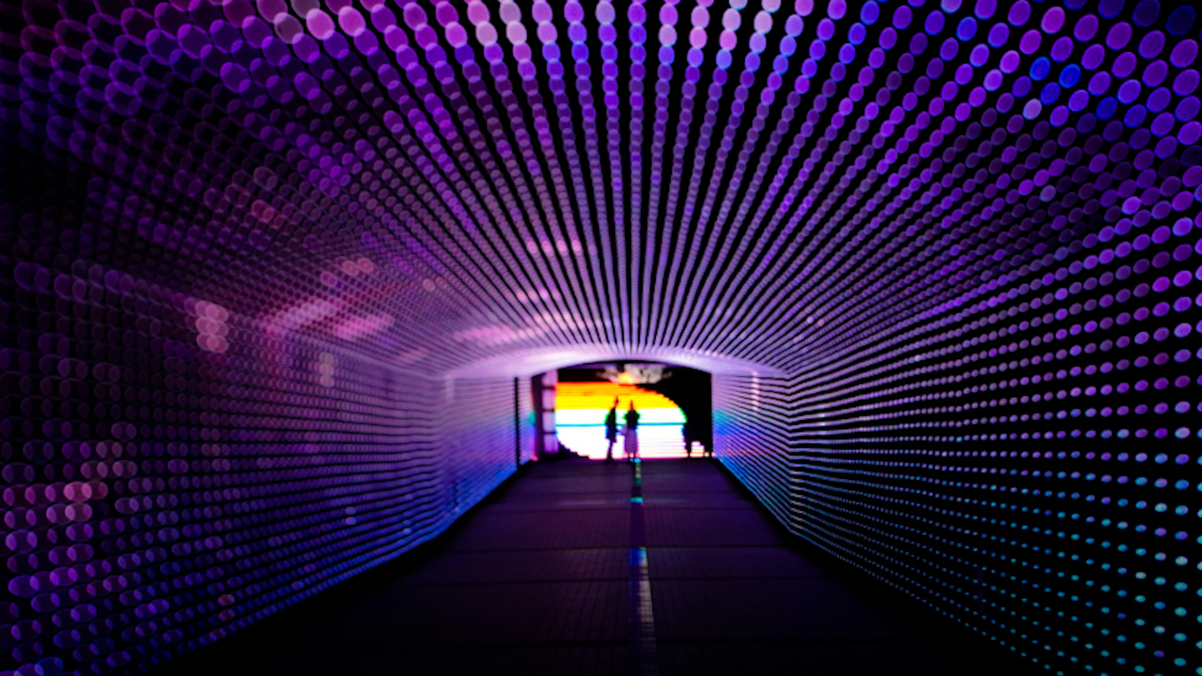 Un tunnel vibrant illuminé par des lumières colorées créant une ambiance artistique