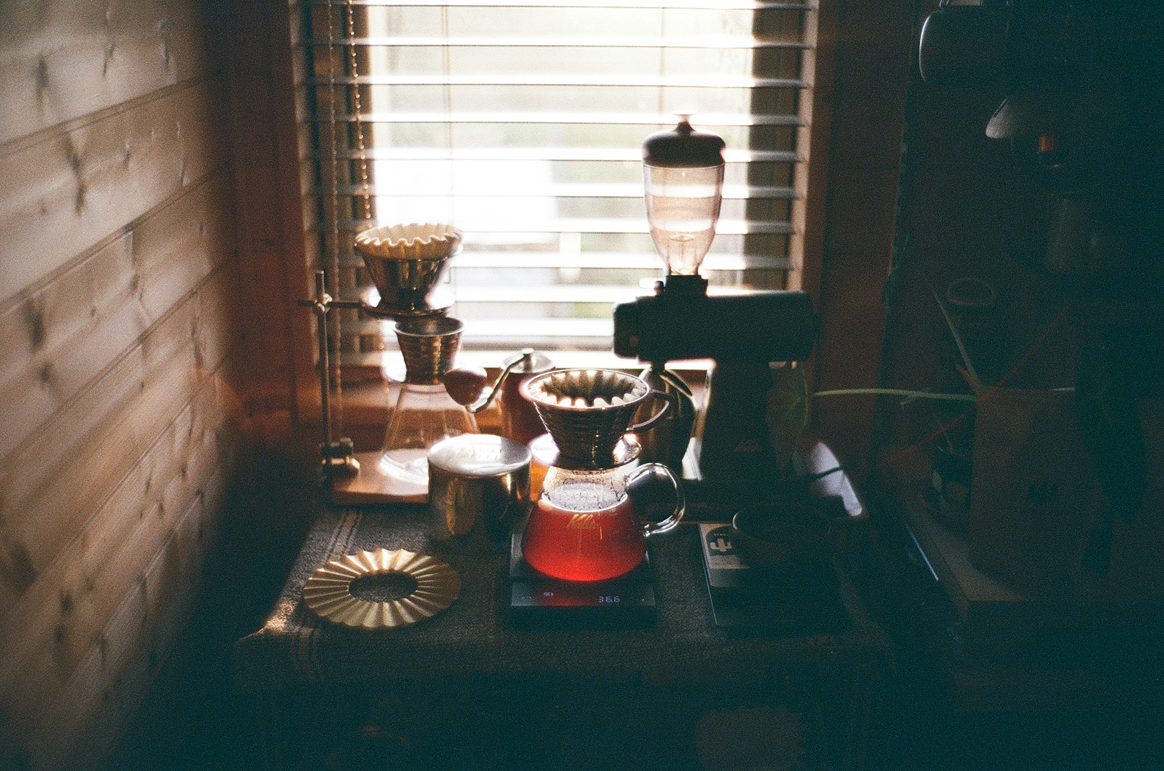 Coffee equipment and teapot arranged on a table by a window with natural light