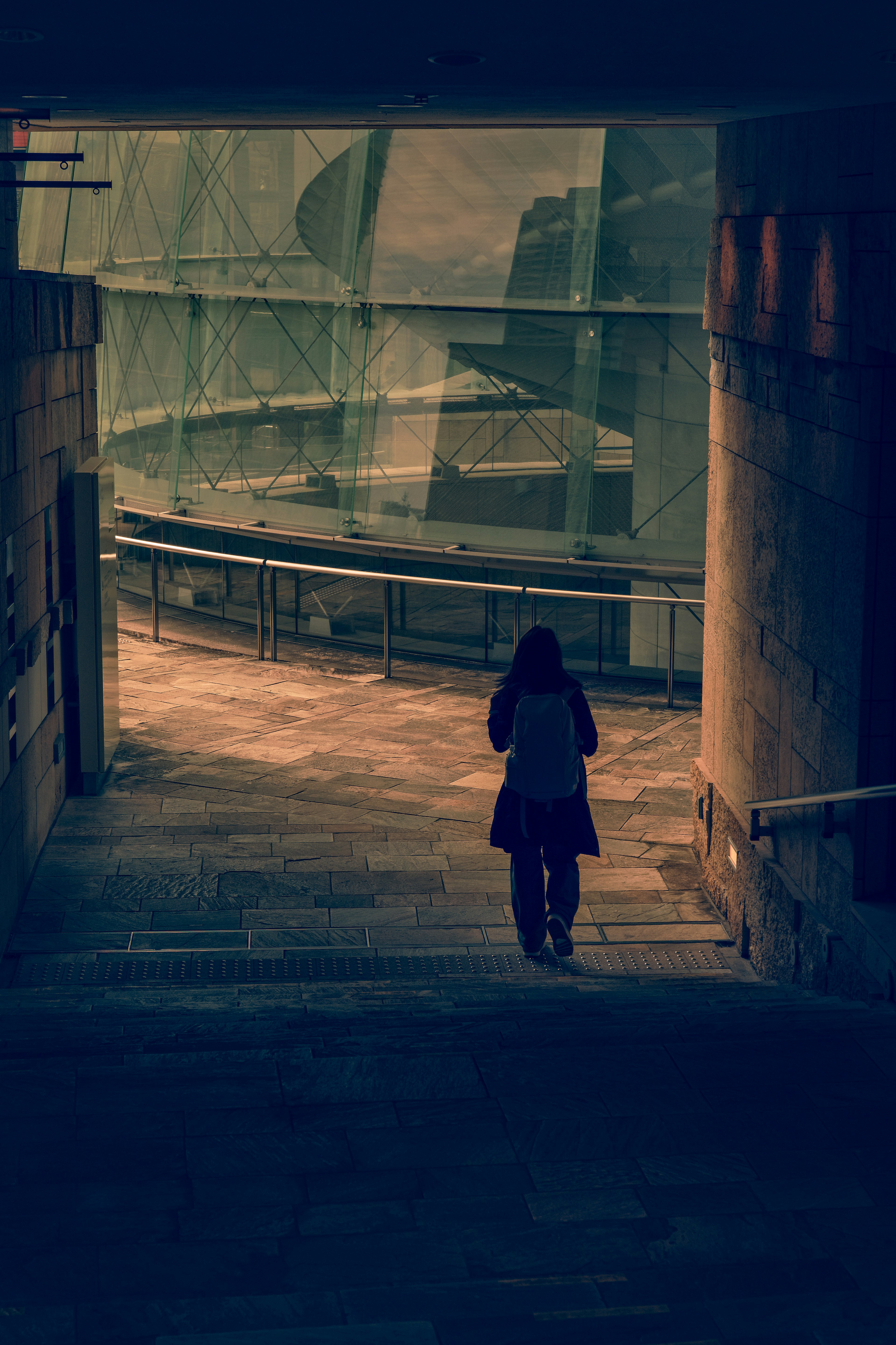 Silhouette d'une personne marchant dans un tunnel sombre avec des structures courbes en arrière-plan