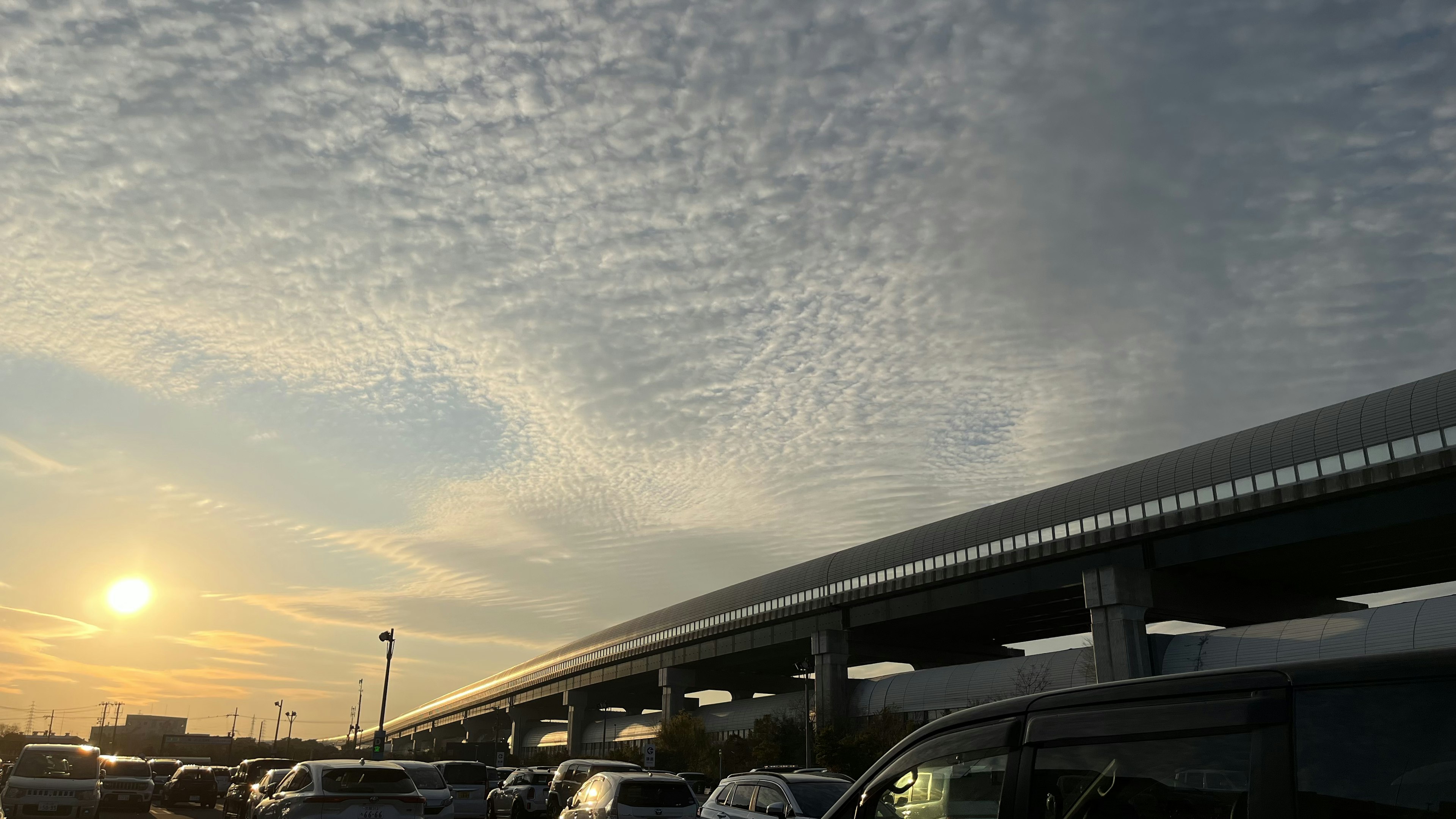 夕阳下波状云彩的景色，停放在高架桥下的汽车