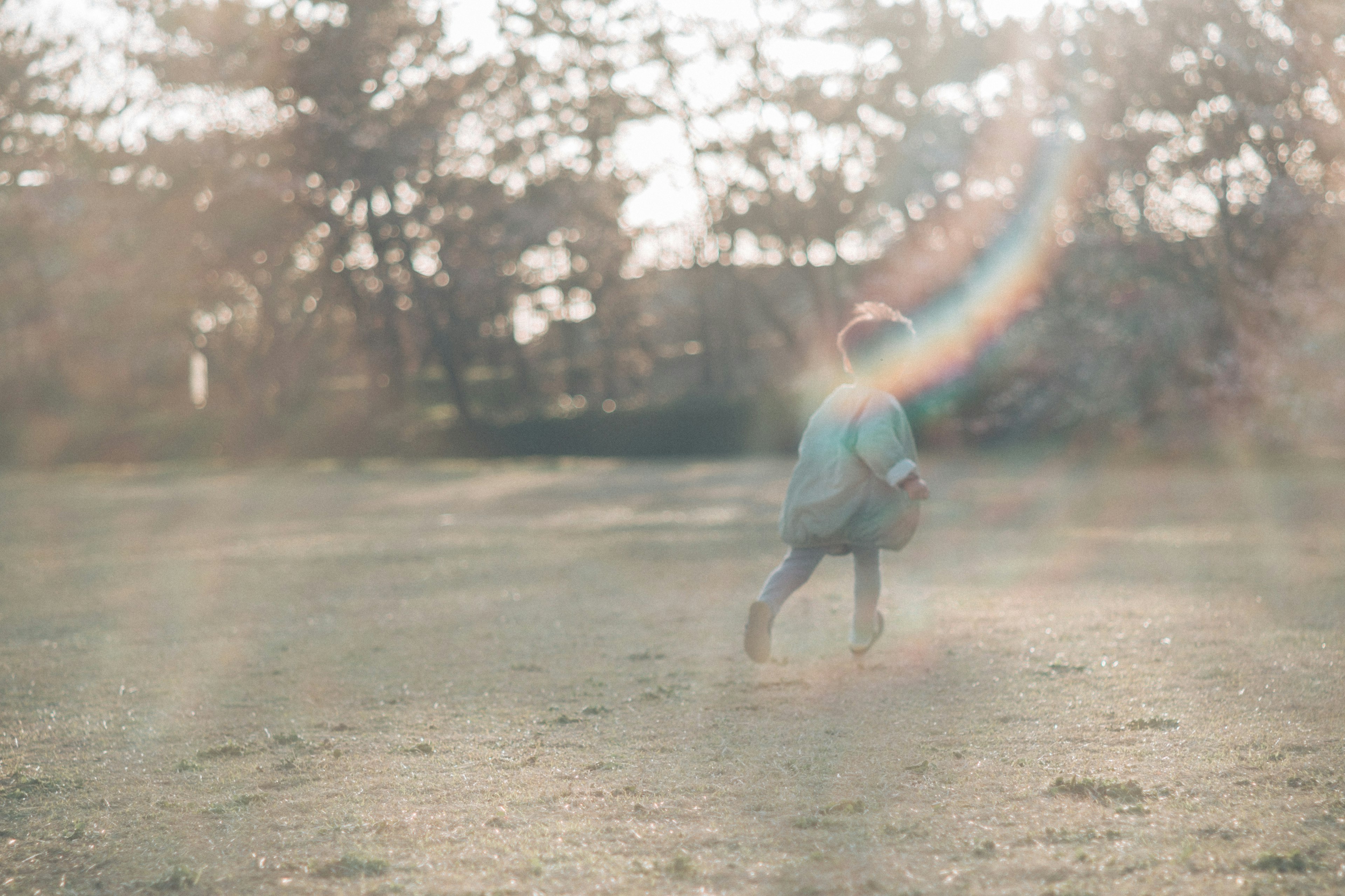 Niño jugando en un parque con luz suave y efecto arcoíris