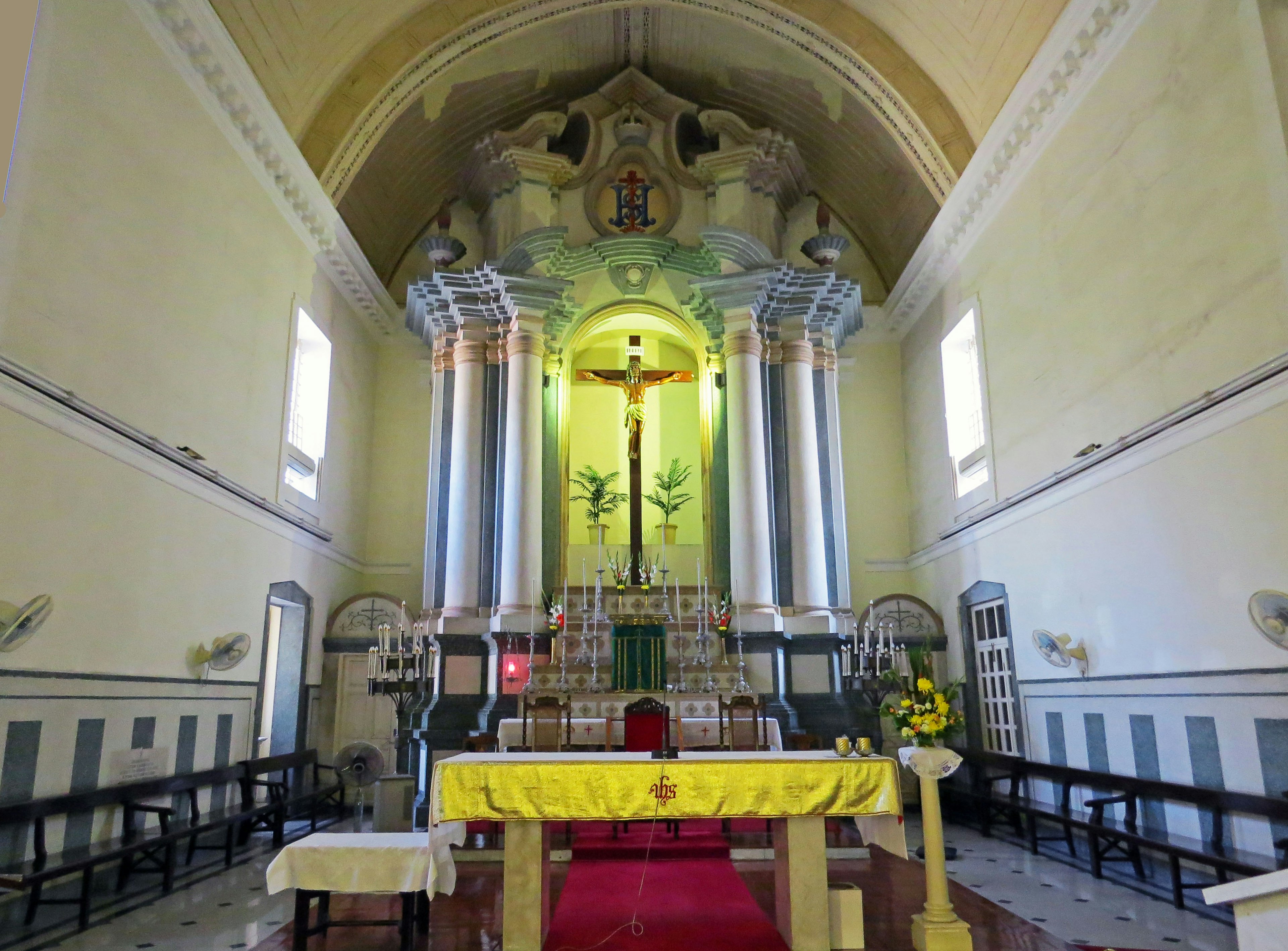 Interno di una chiesa con un grande altare e croce su pareti colorate