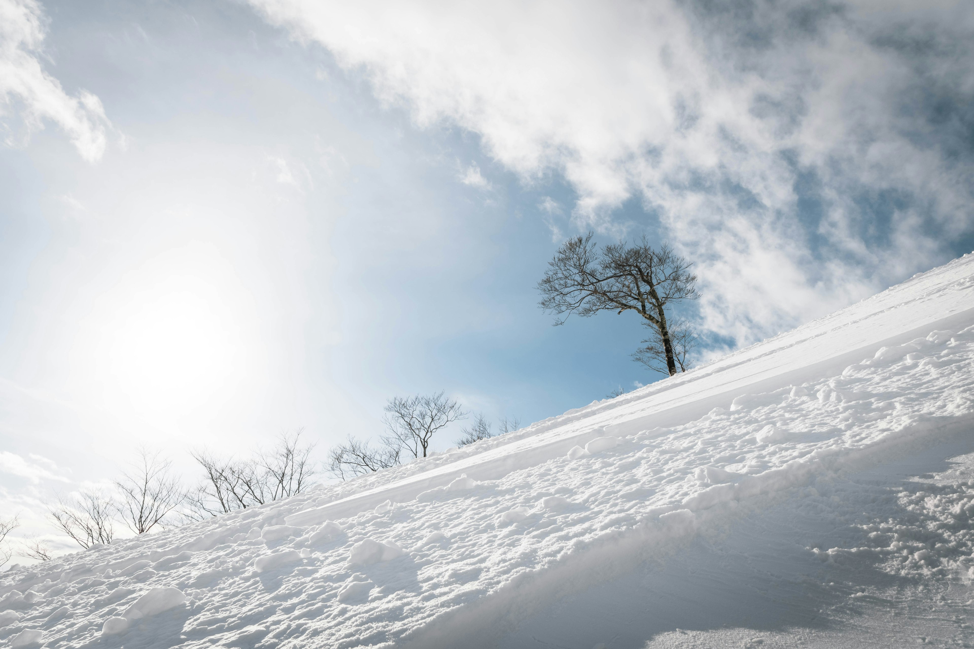 雪に覆われた斜面と青空に浮かぶ雲の風景