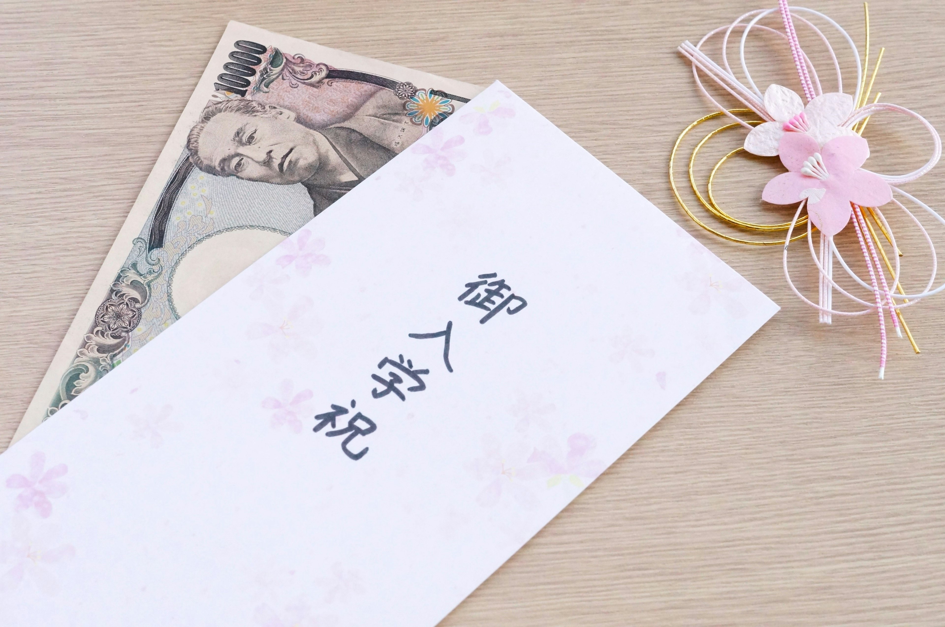 An envelope with Japanese characters and decorative flowers alongside banknotes