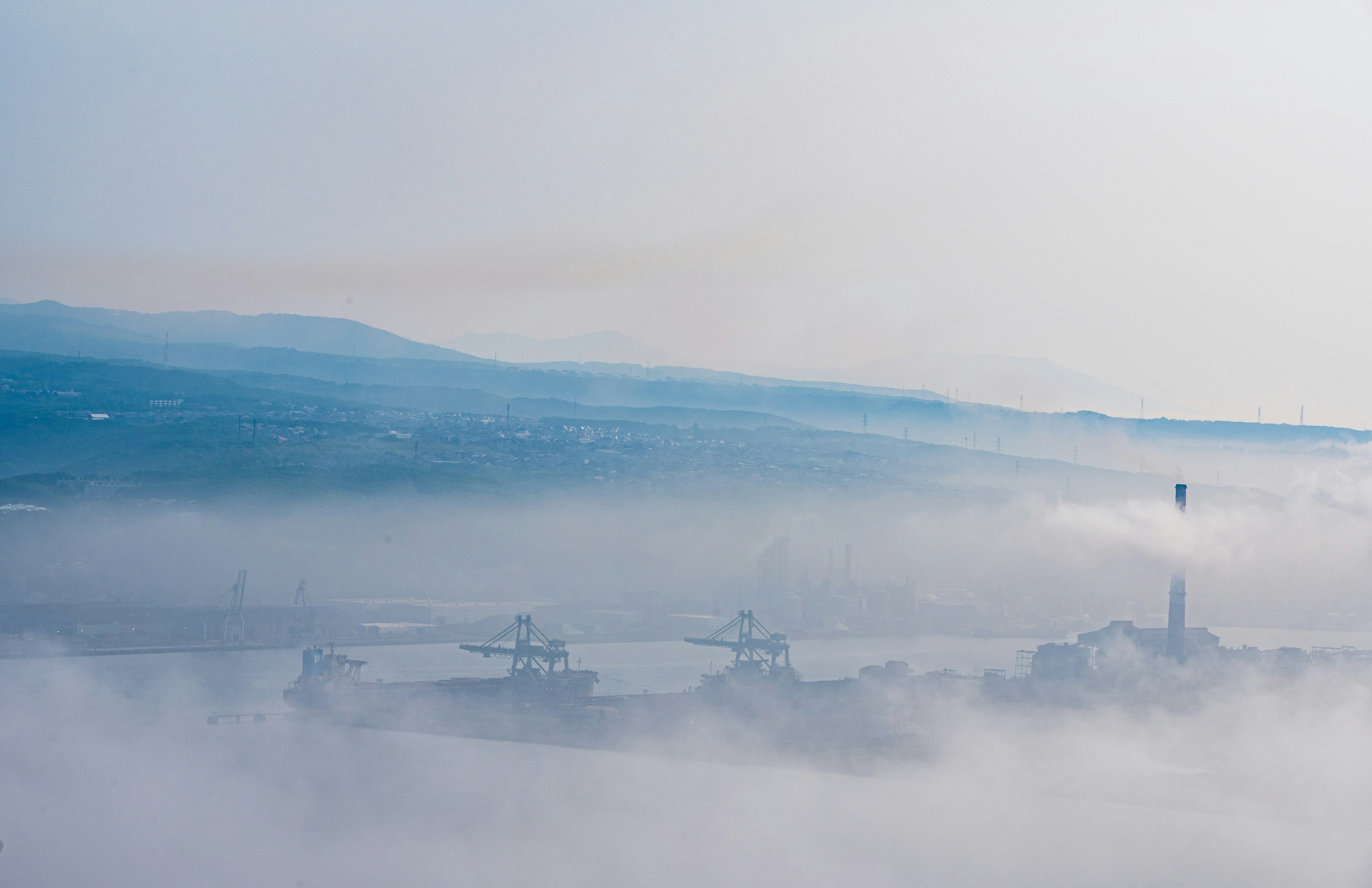 Vue du port enveloppée de brouillard bleu avec des montagnes lointaines