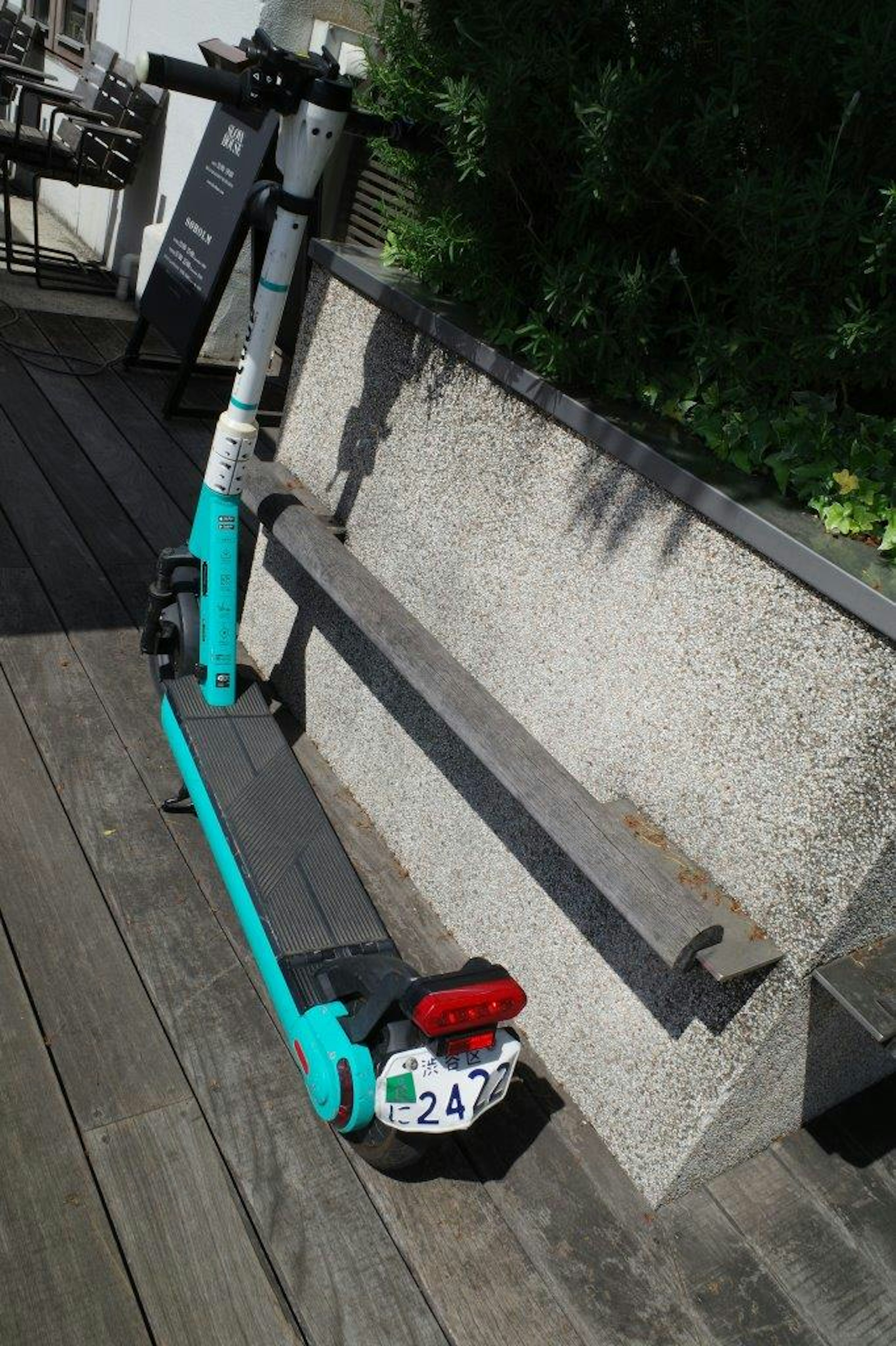 A blue electric scooter parked next to a bench