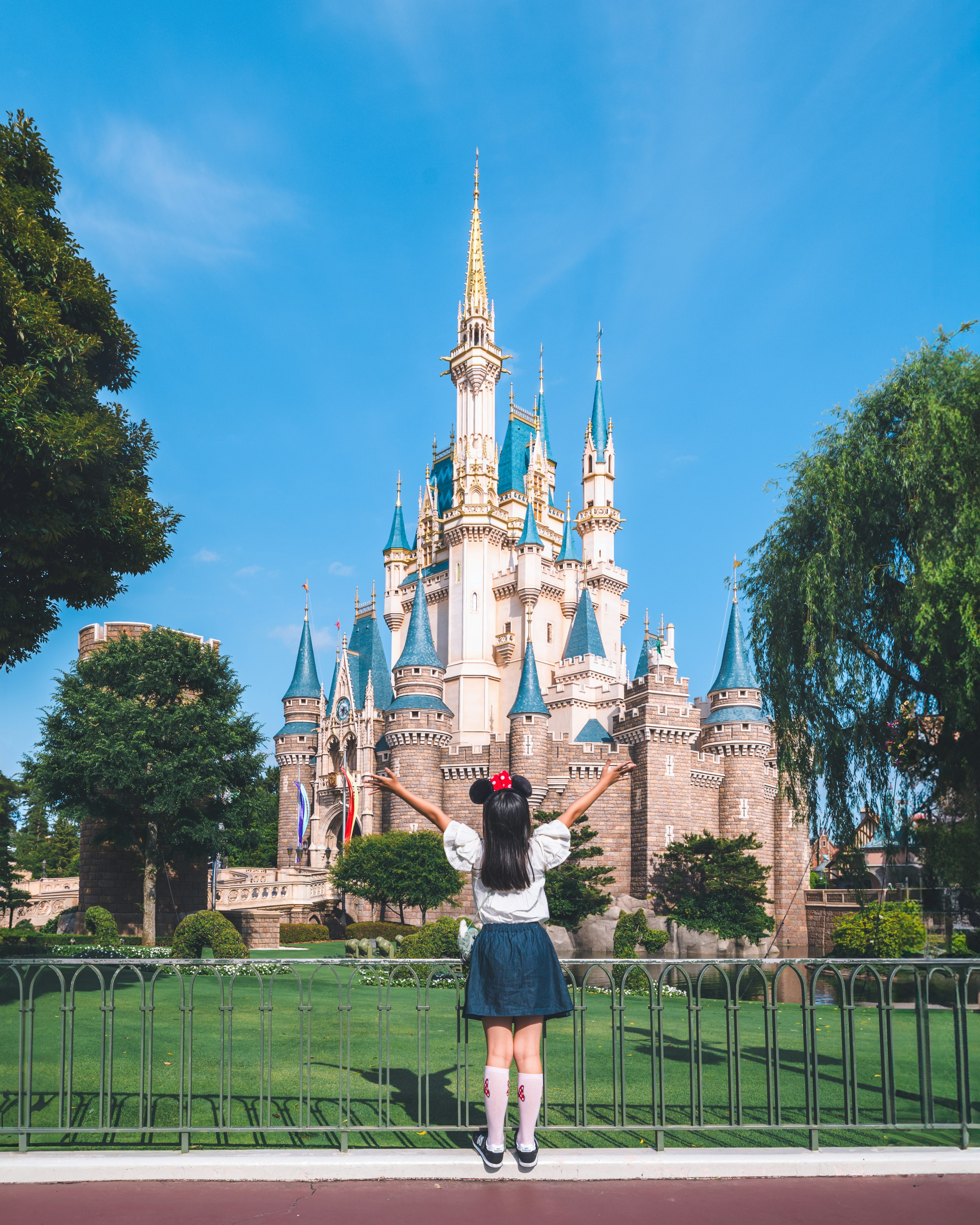 Fille en jupe avec des couettes devant un château féérique