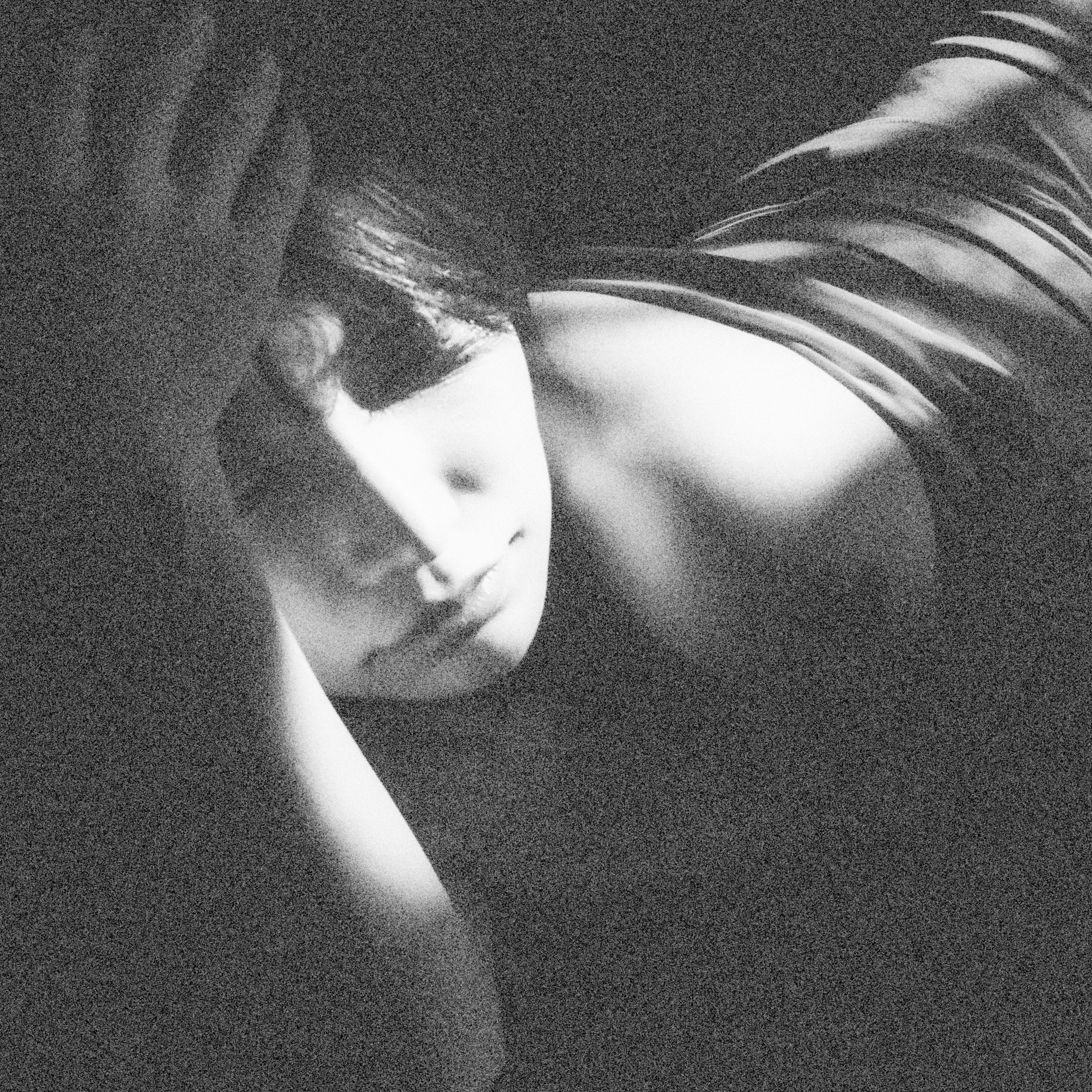 Image en noir et blanc d'une femme allongée sur un fond sombre contraste frappant de lumière et d'ombre