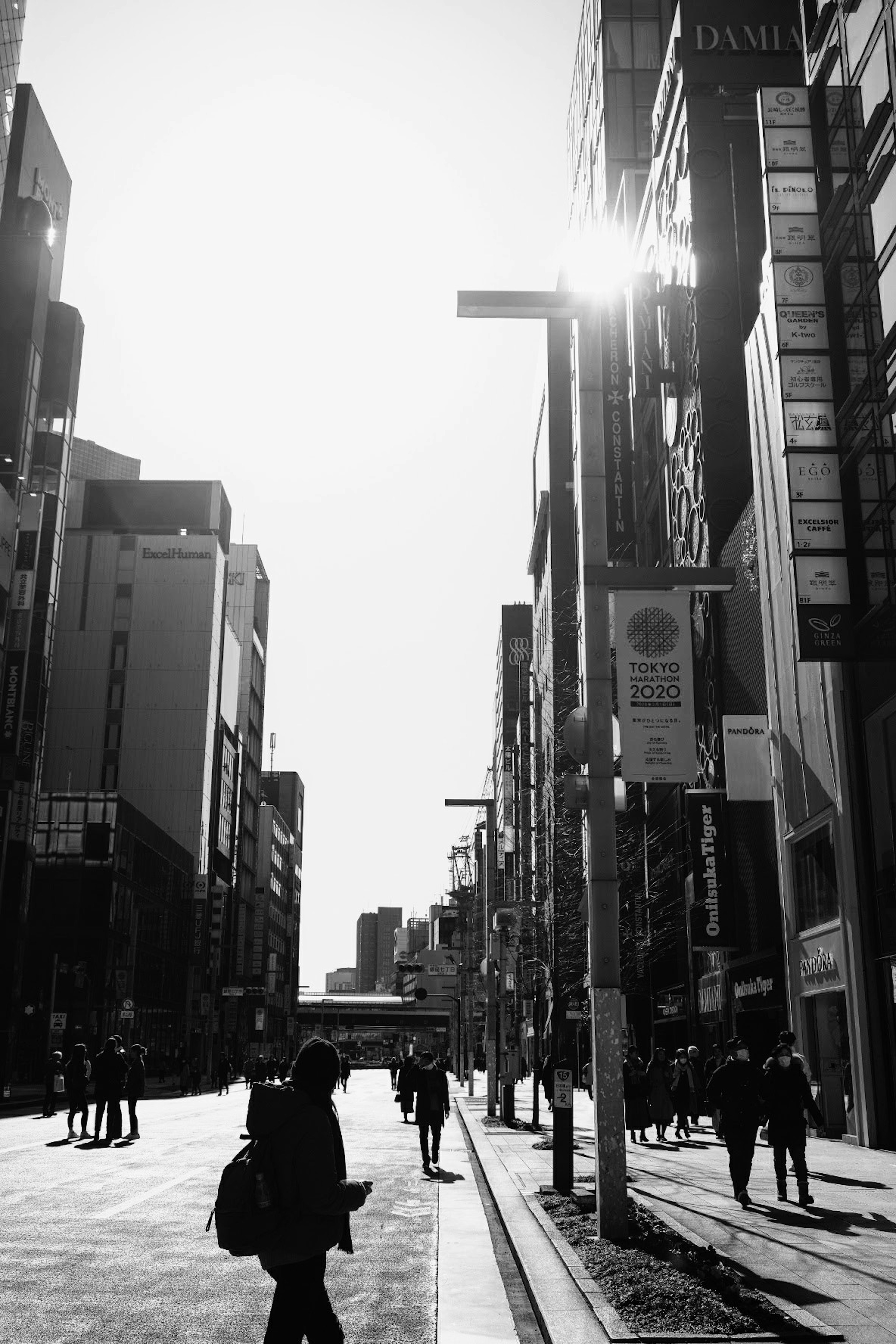 Scène urbaine en noir et blanc avec des silhouettes de bâtiments et de piétons dans une rue