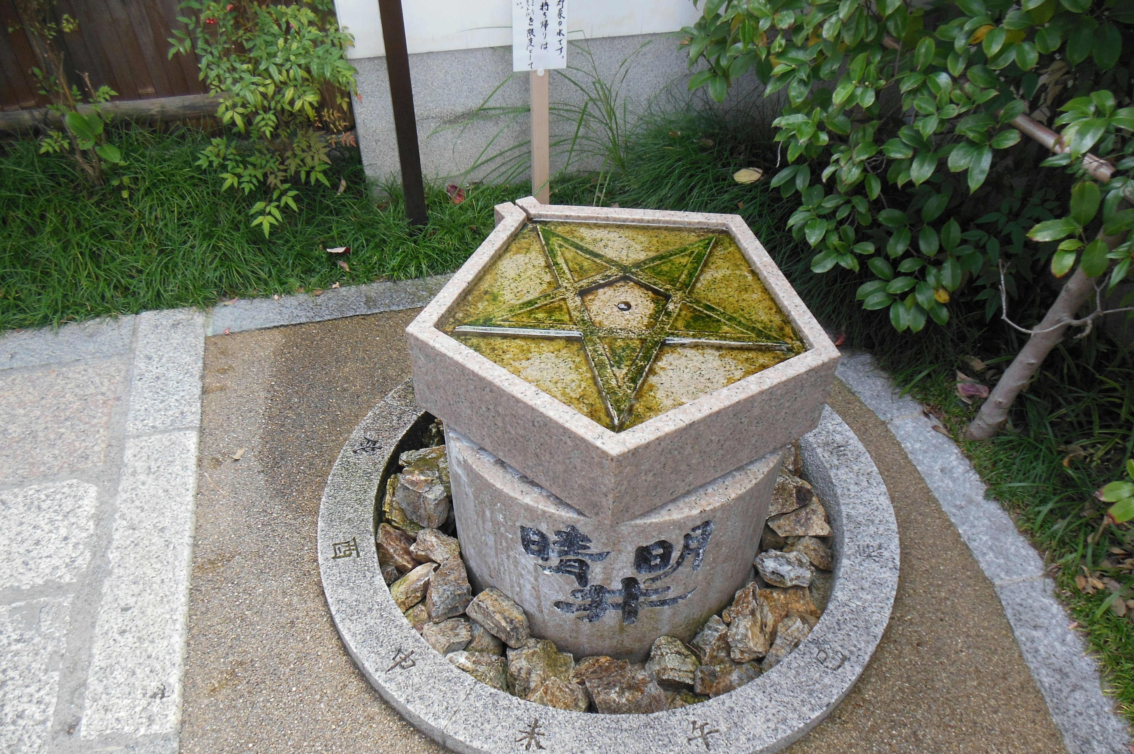 Hexagonal water basin surrounded by stones in a garden setting