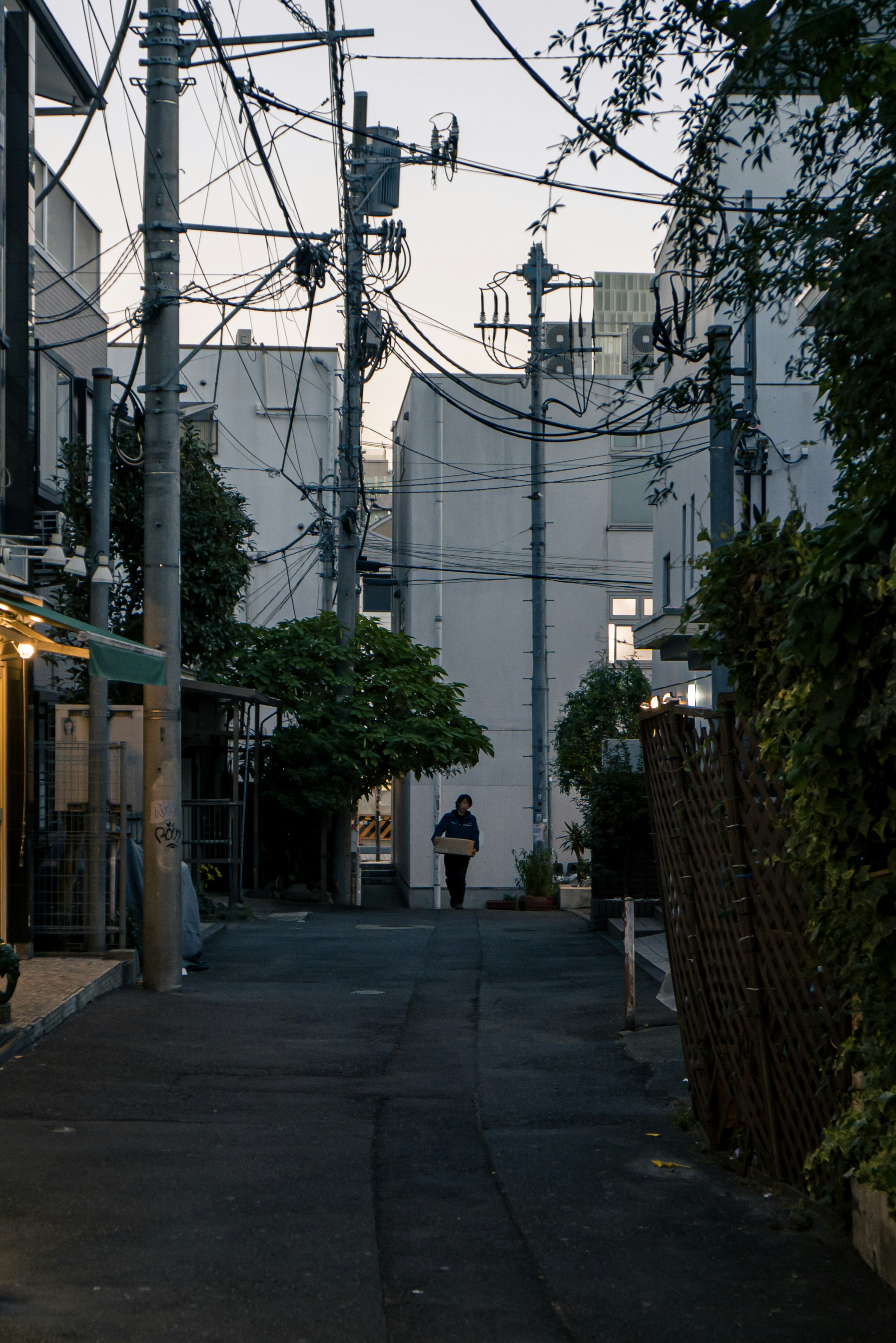 Narrow alley with a person standing and intersecting power lines