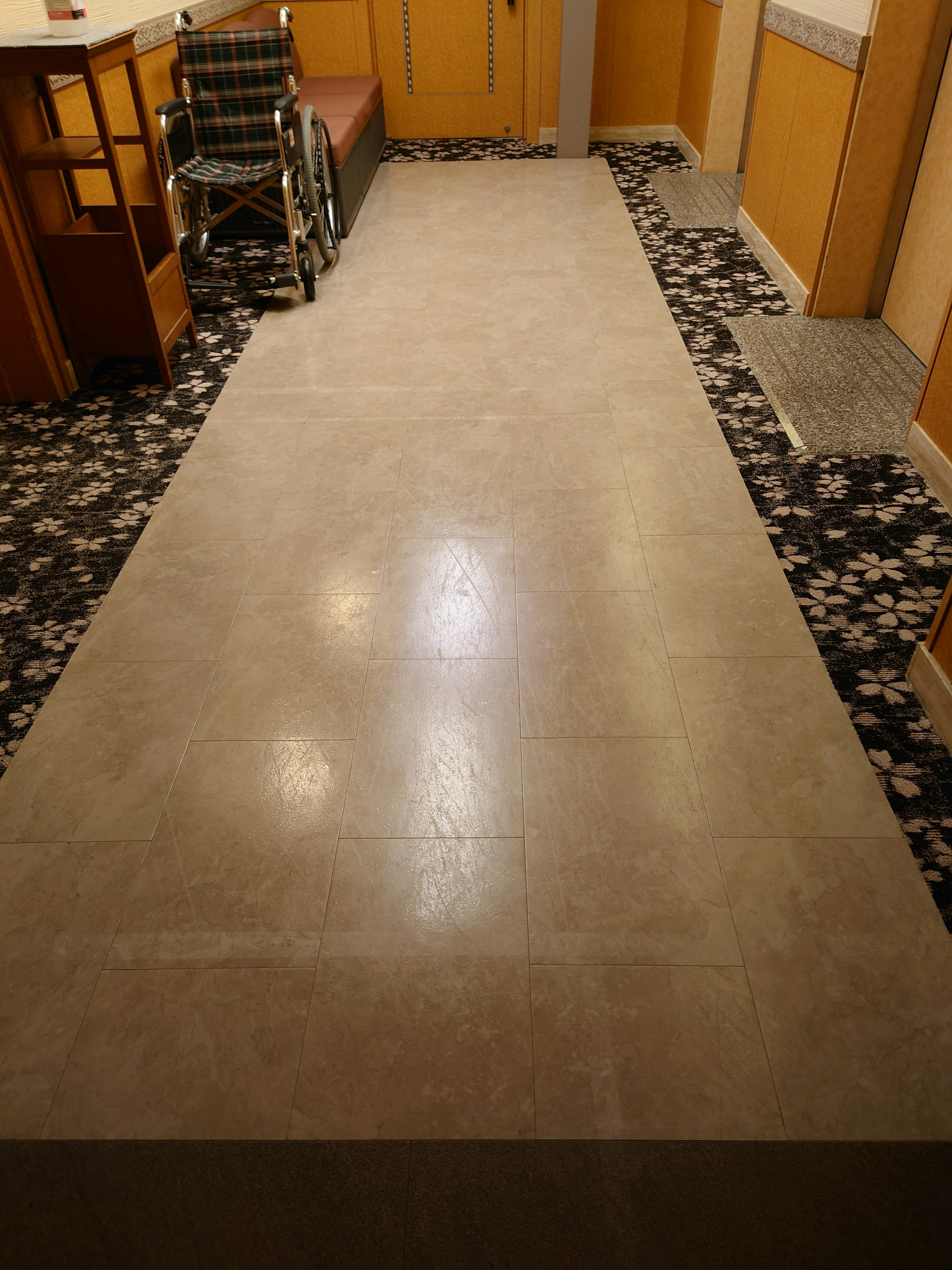 Suelo de colores brillantes con alfombra de flores en un pasillo interior con una silla de ruedas