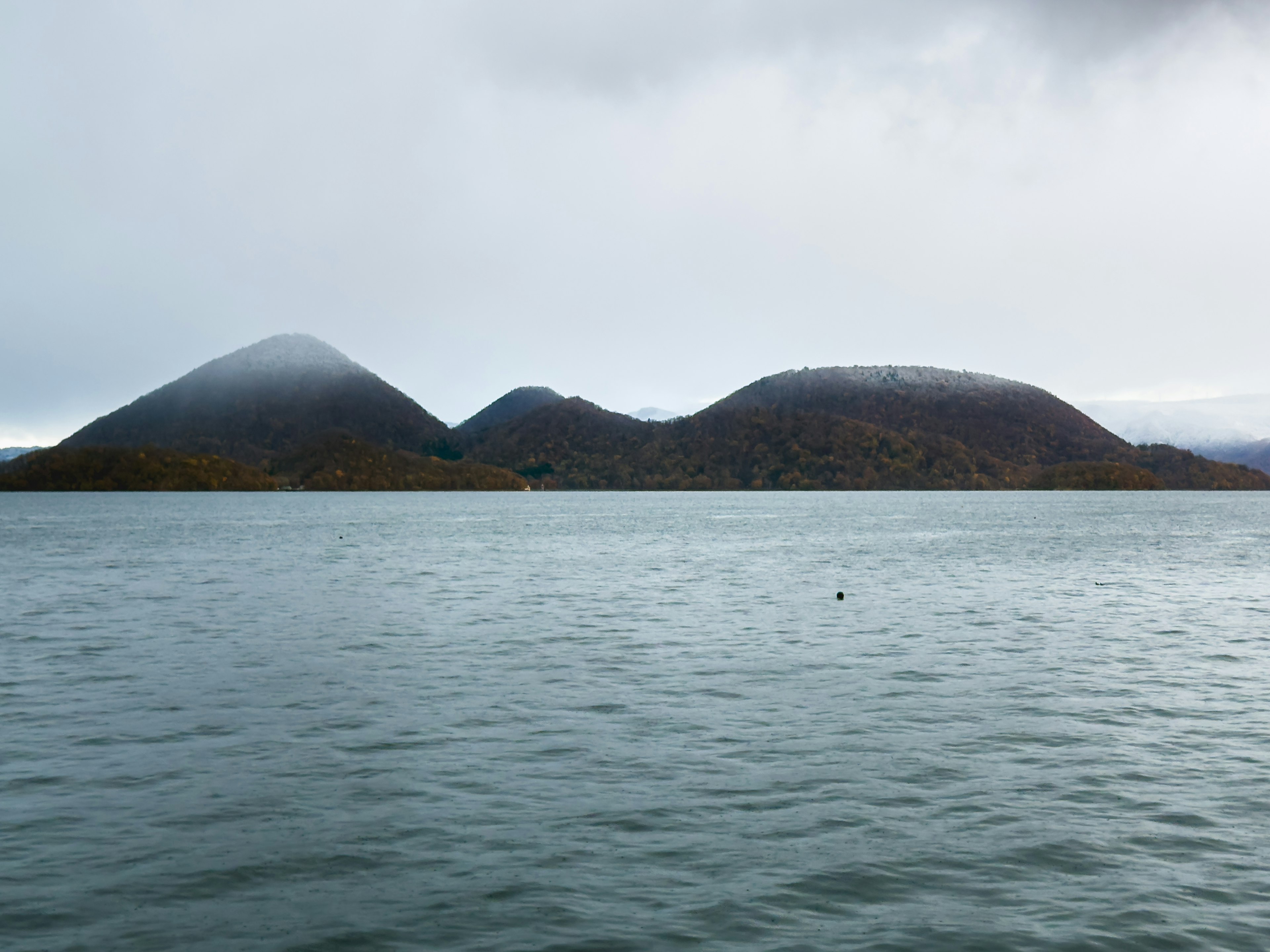 Gunung yang diselimuti kabut dengan danau tenang