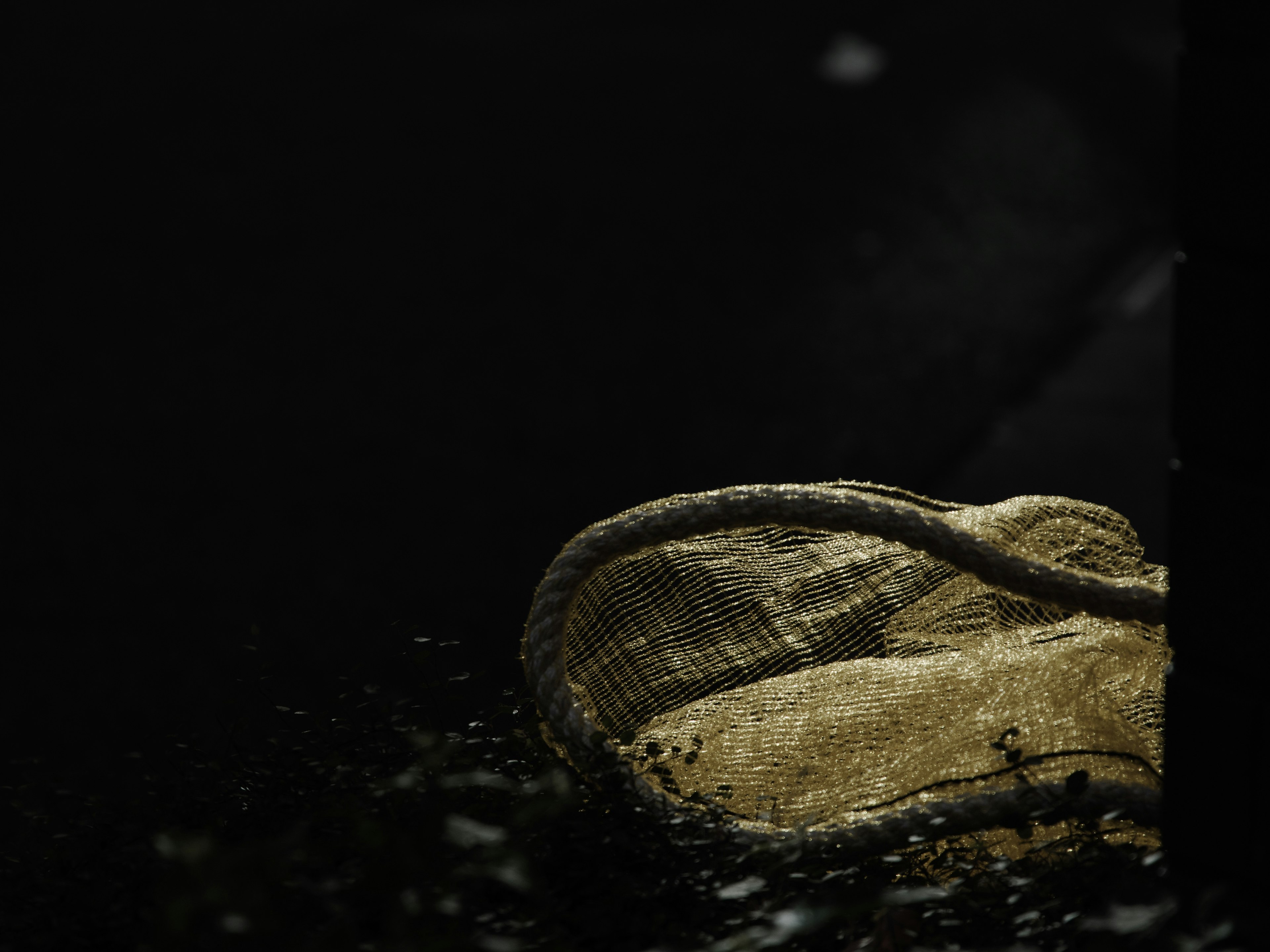 Partial view of an old burlap sack against a dark background