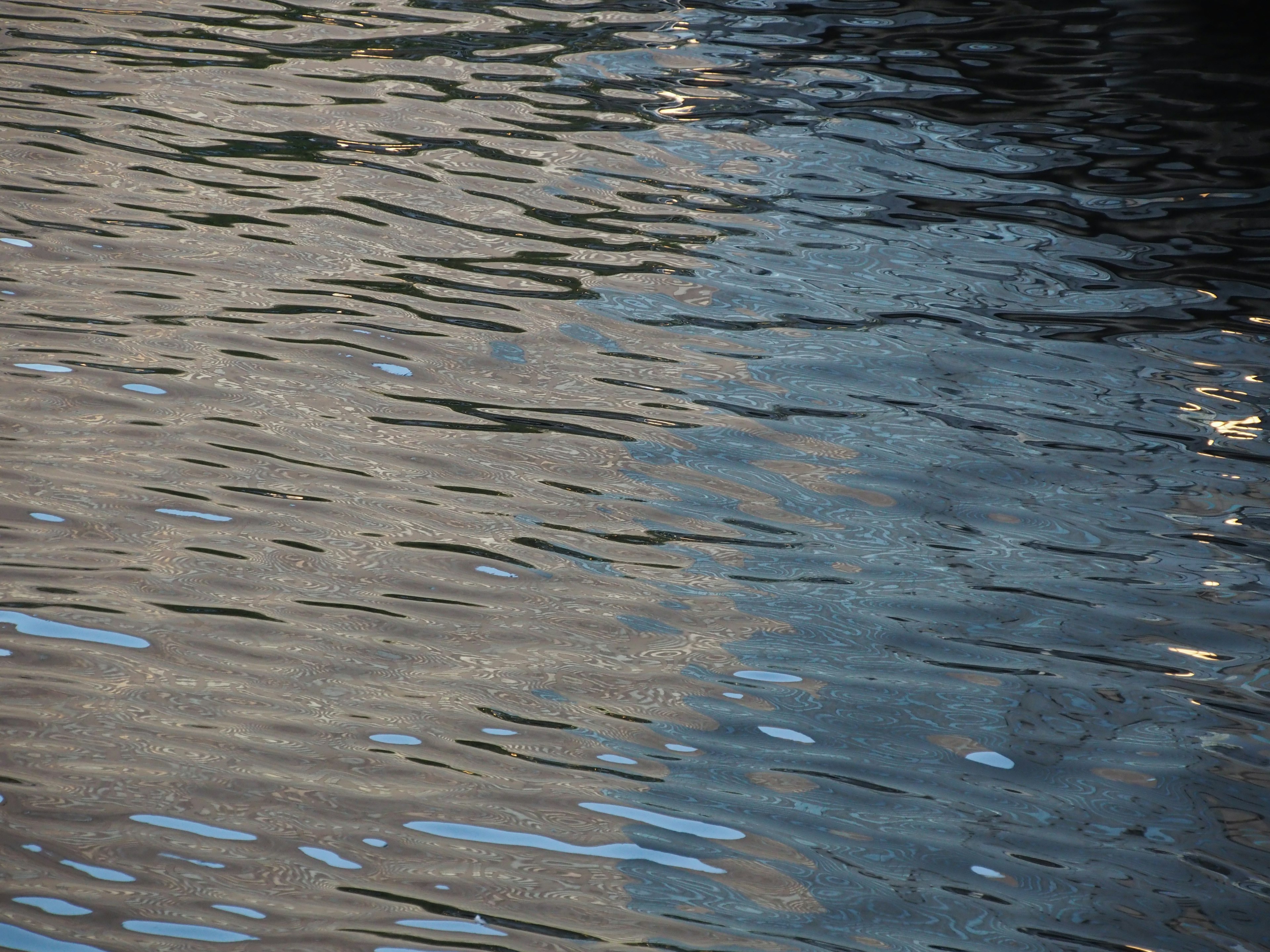 Ruhige Wasseroberfläche mit Reflexionen und Wellen