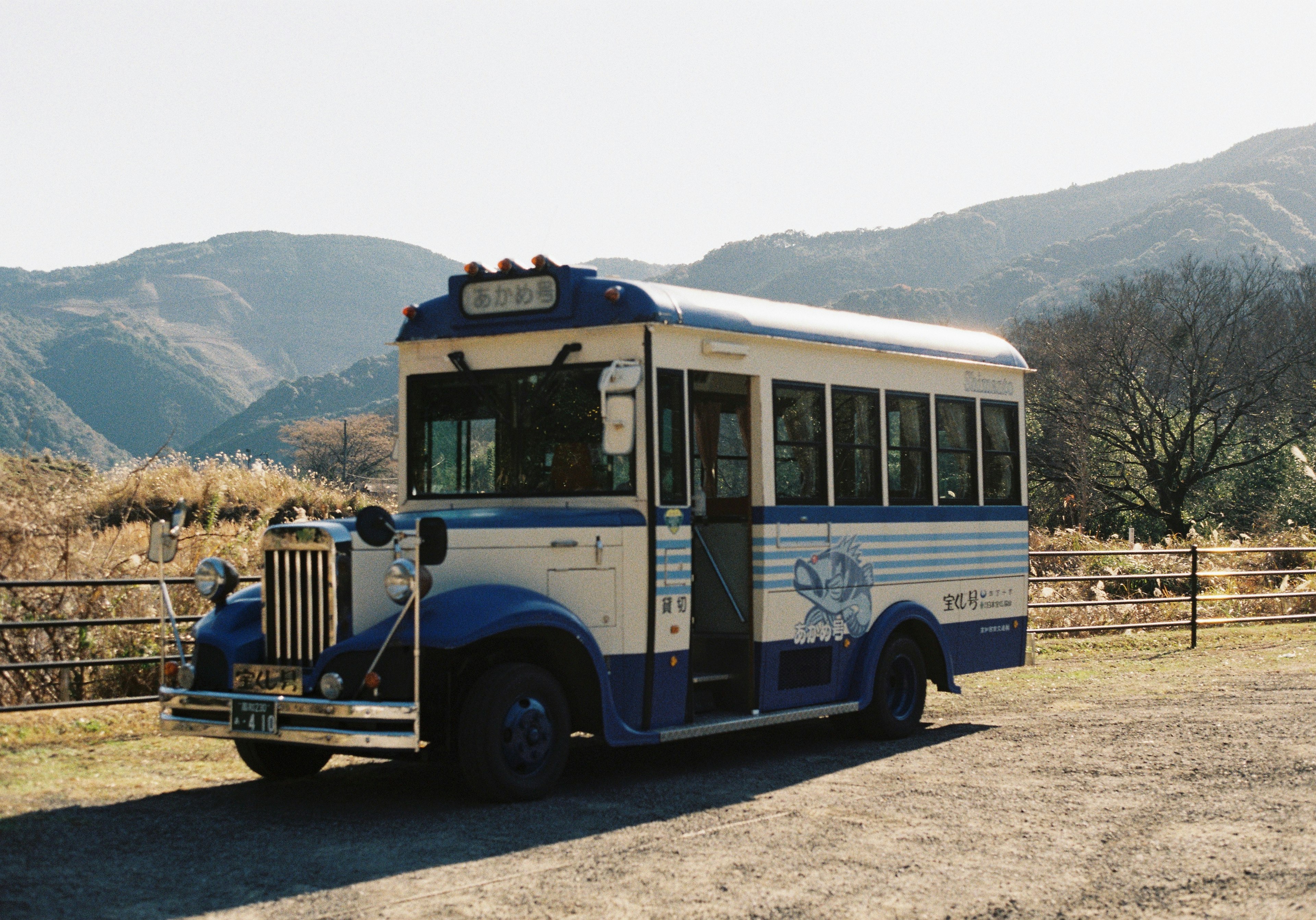 Un bus classique bleu et blanc garé devant un paysage montagneux