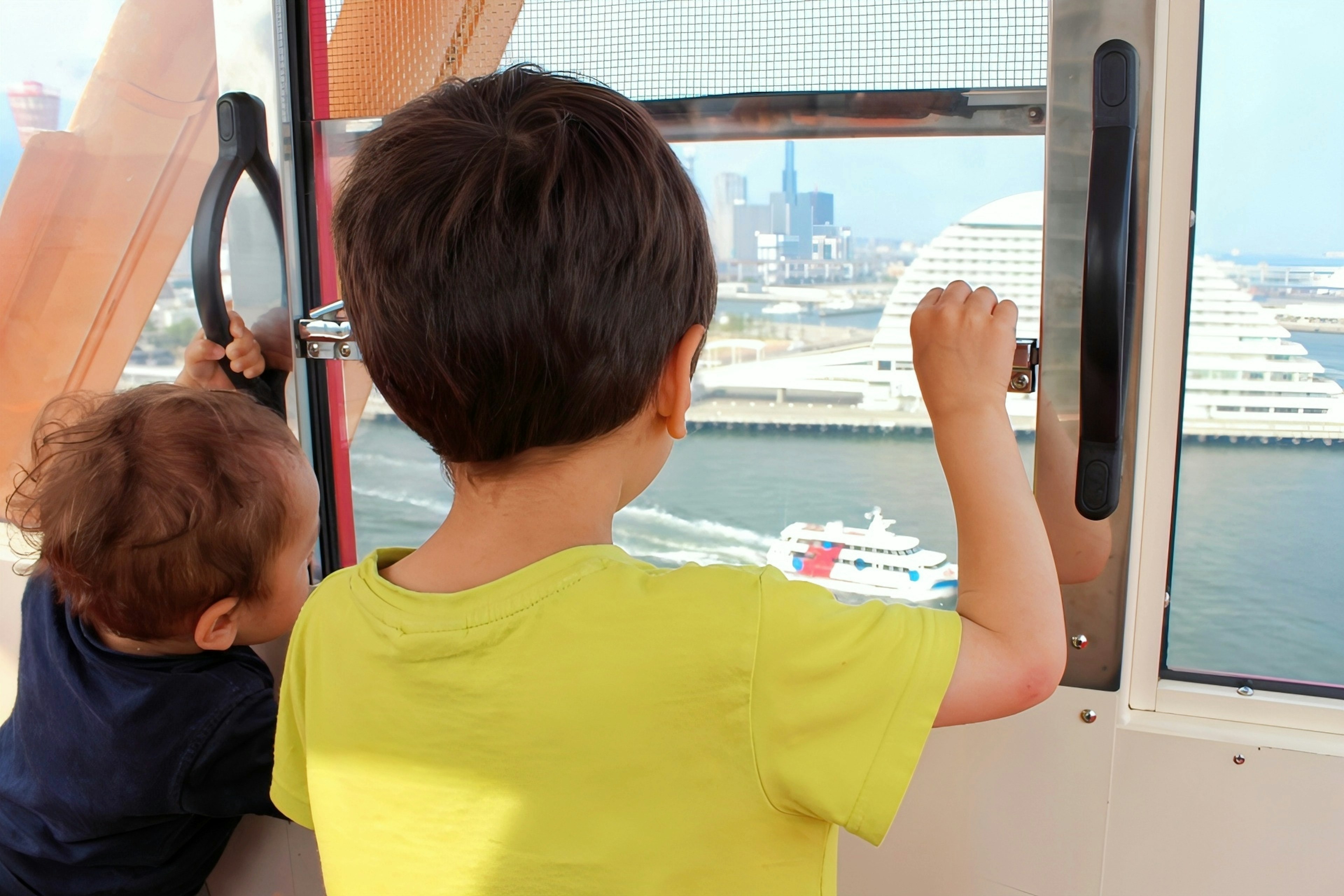 Children looking out of a ferris wheel cabin at a city view