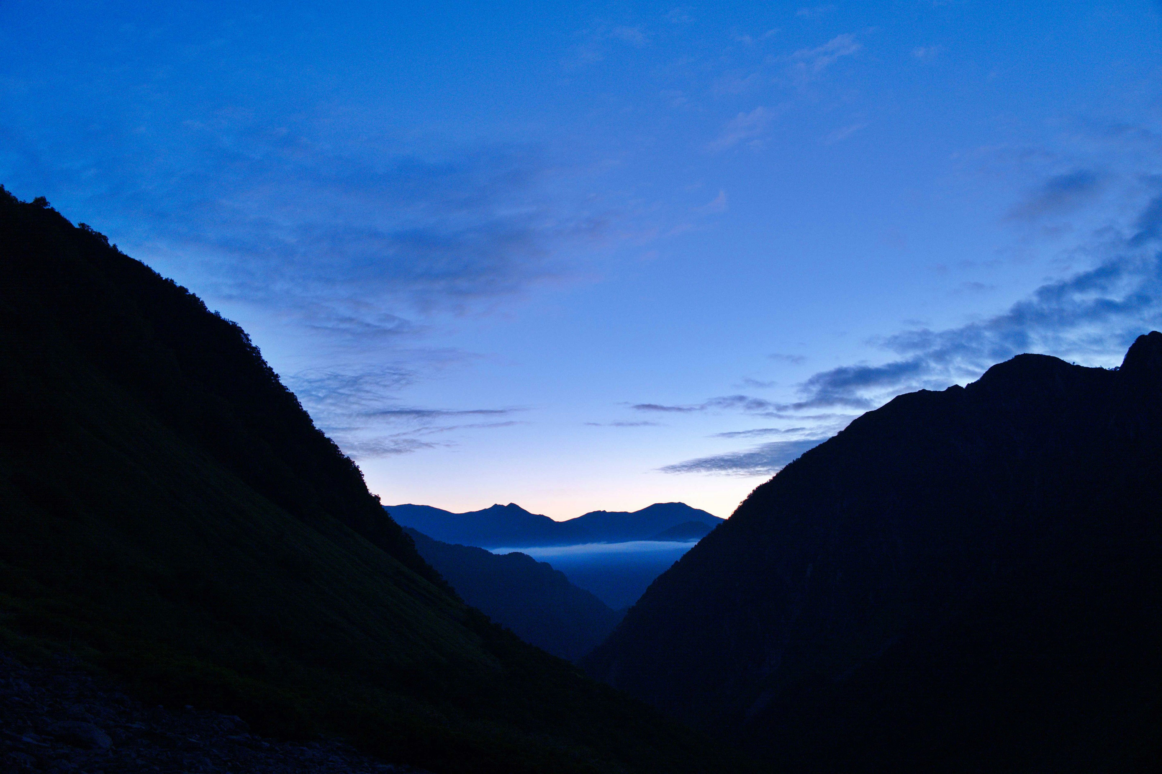 Silueta de montañas contra un cielo azul al amanecer