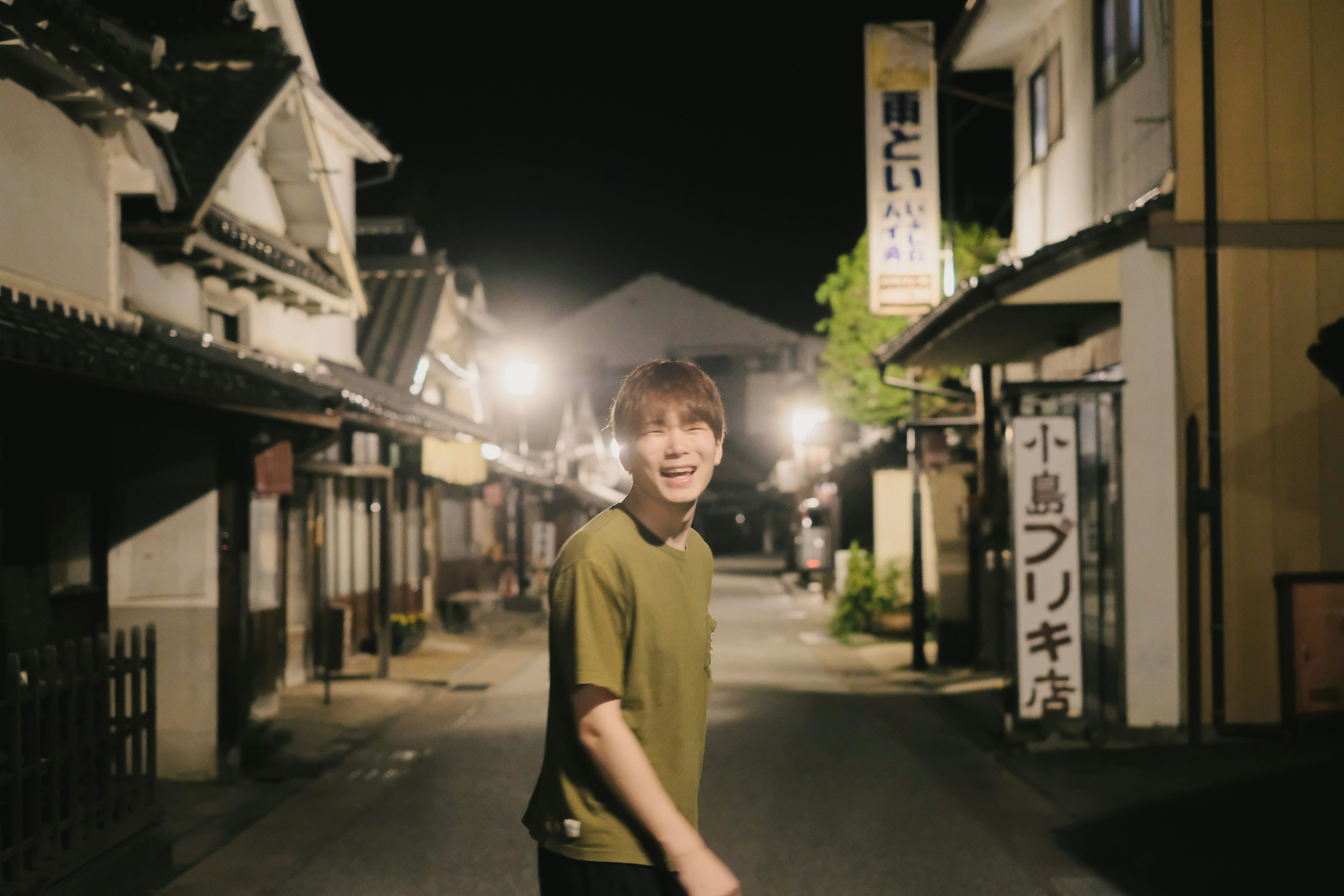 Un joven sonriente caminando por una calle tranquila de noche