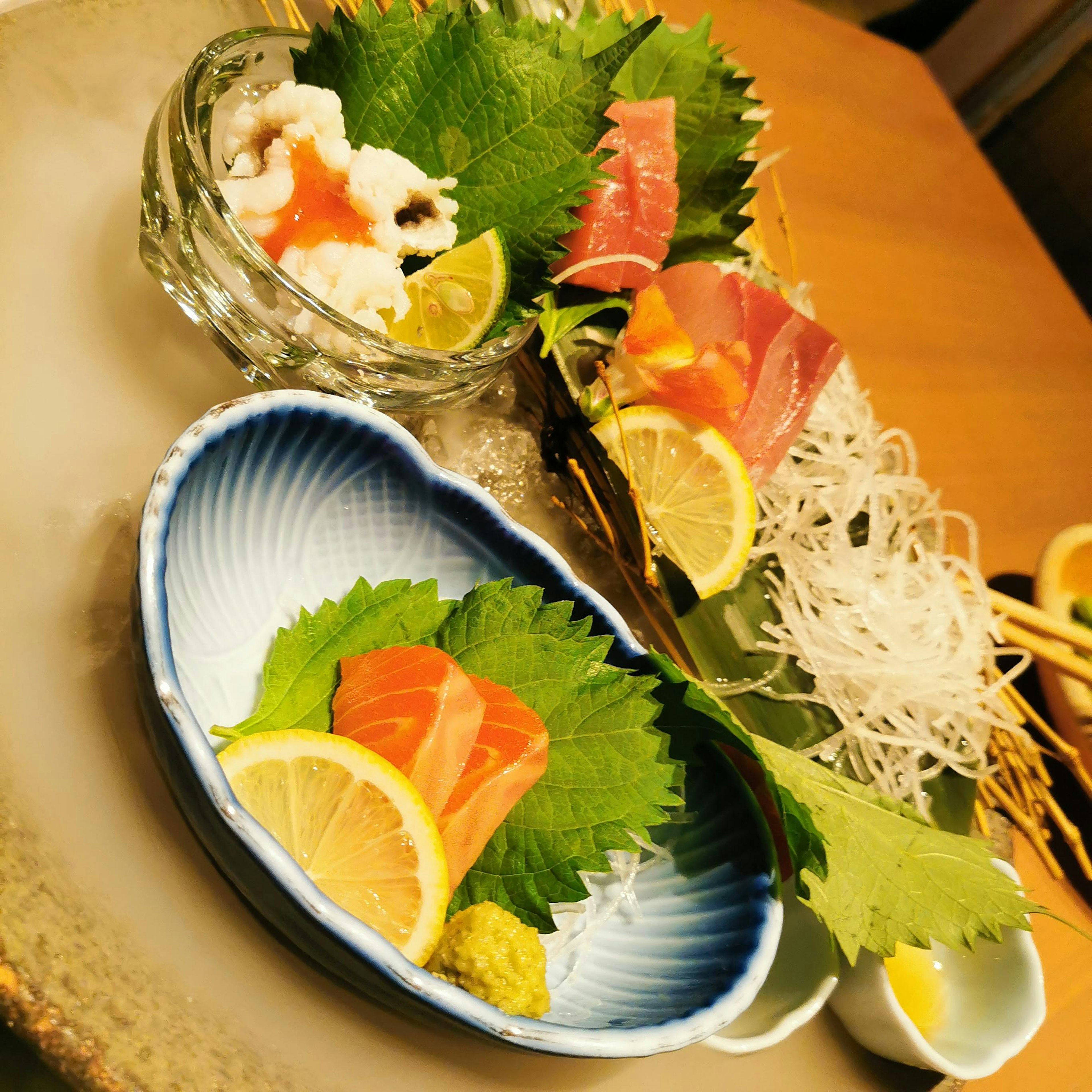 Fresh sashimi arranged with citrus garnishes and shiso leaves