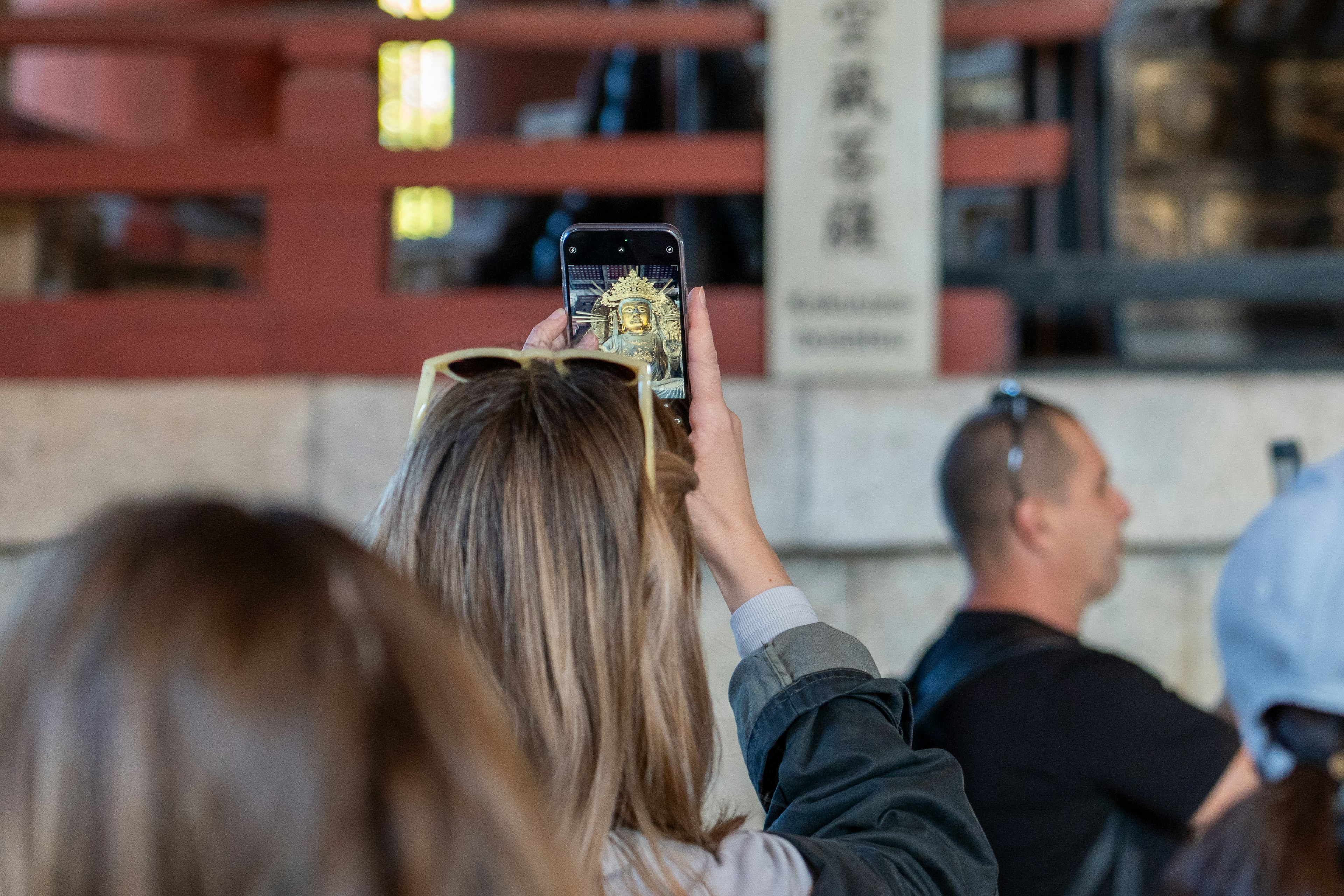 スマートフォンで写真を撮る女性の後ろ姿と観光名所の背景