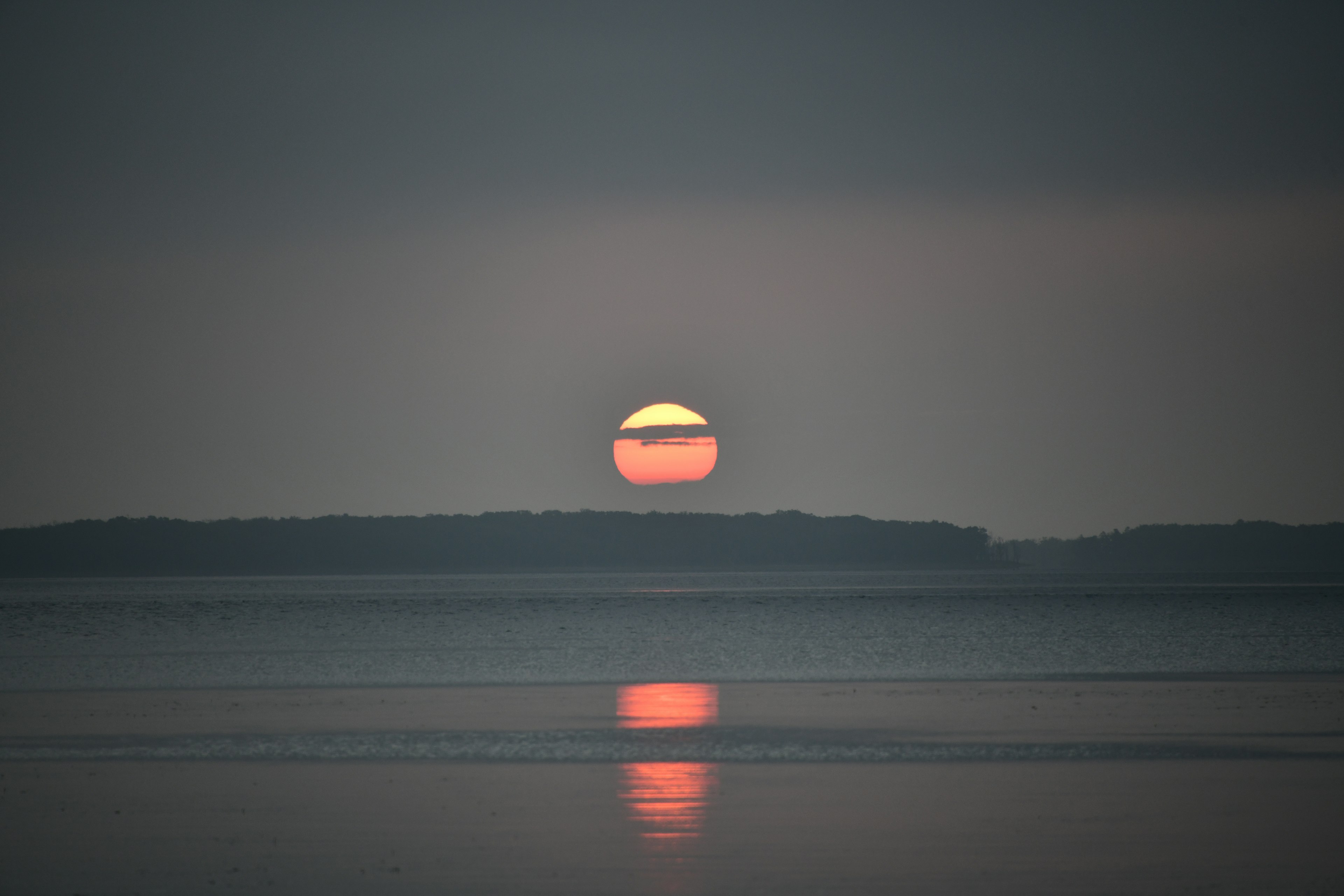 Ruhige Meereslandschaft mit Sonnenuntergang, der sich im Wasser spiegelt