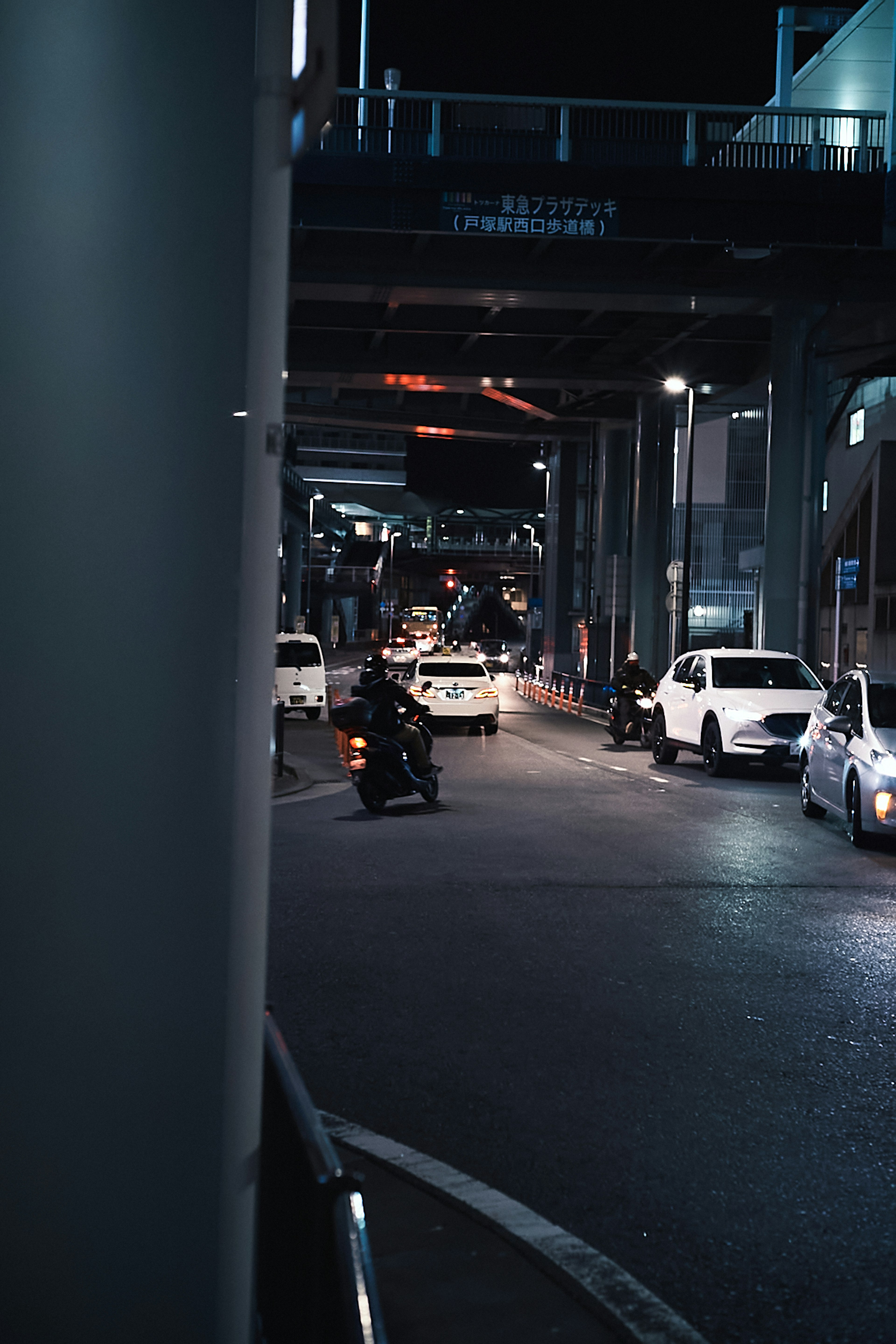 Nachtansicht einer Stadtstraße mit Autos und einem Motorrad