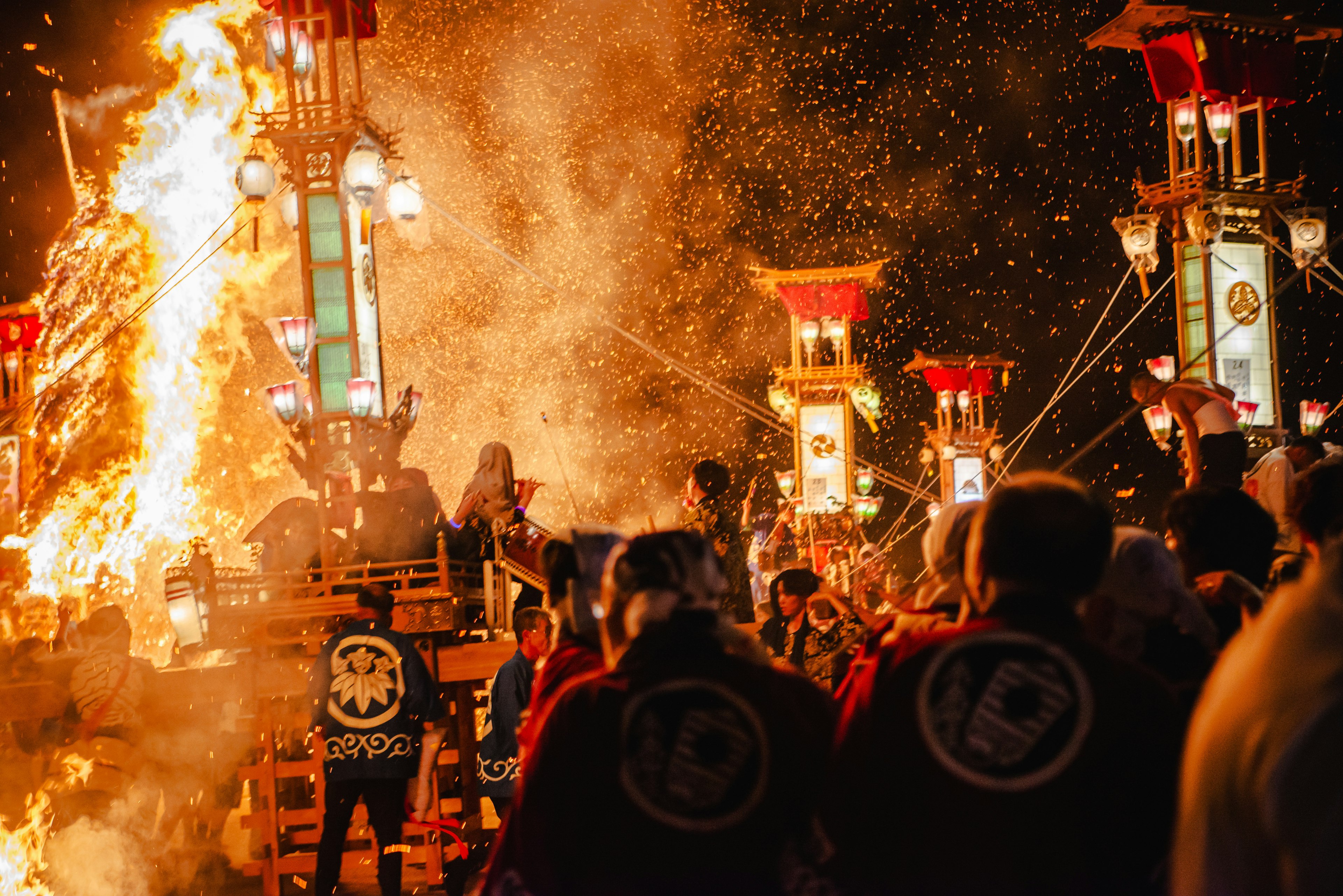 Festivalteilnehmer mit traditionellen Wagen vor einer Feuerkulisse