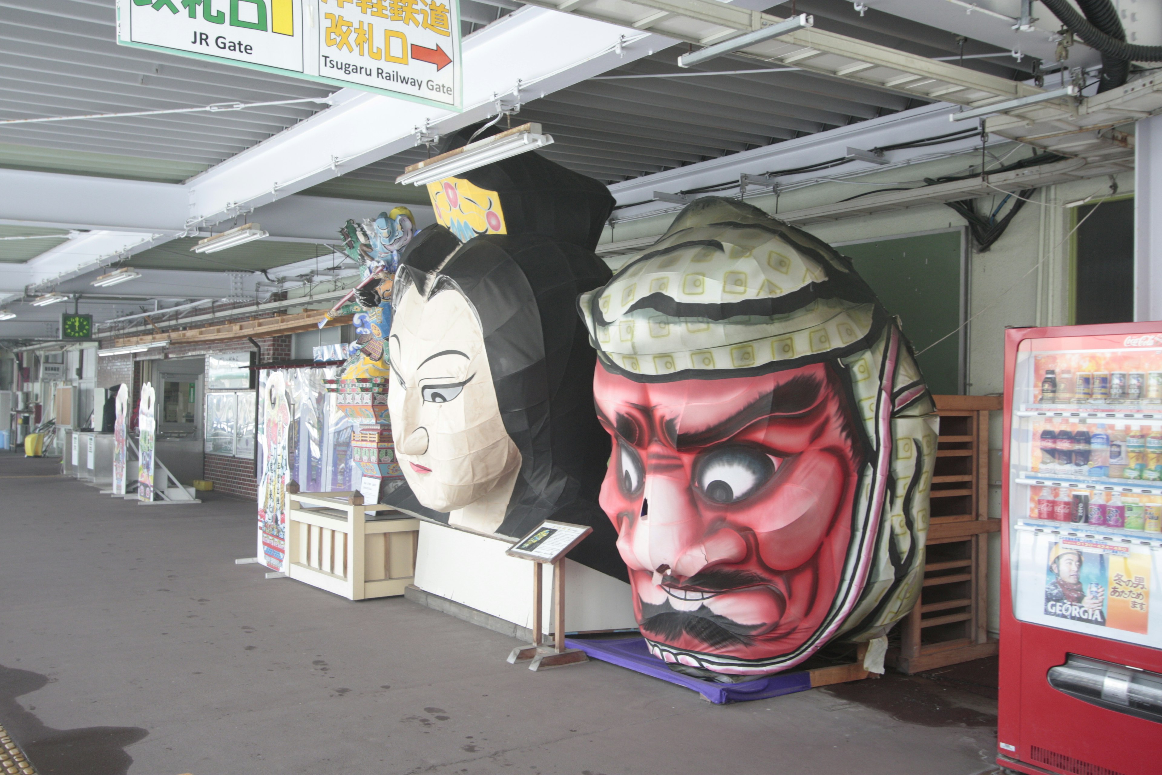 Máscaras tradicionales gigantes exhibidas en una estación de tren