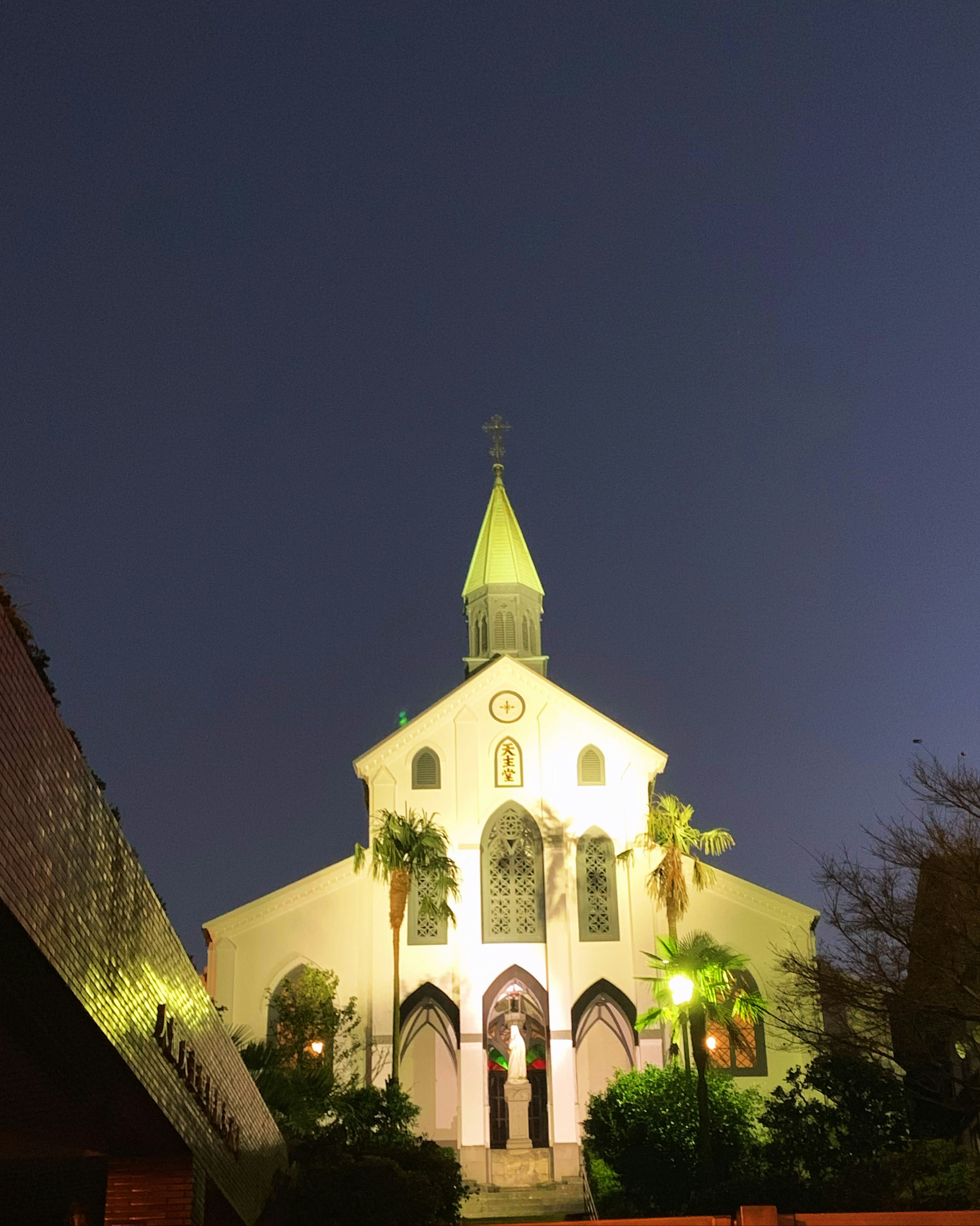 Exterior de una iglesia iluminada por la noche con características arquitectónicas góticas