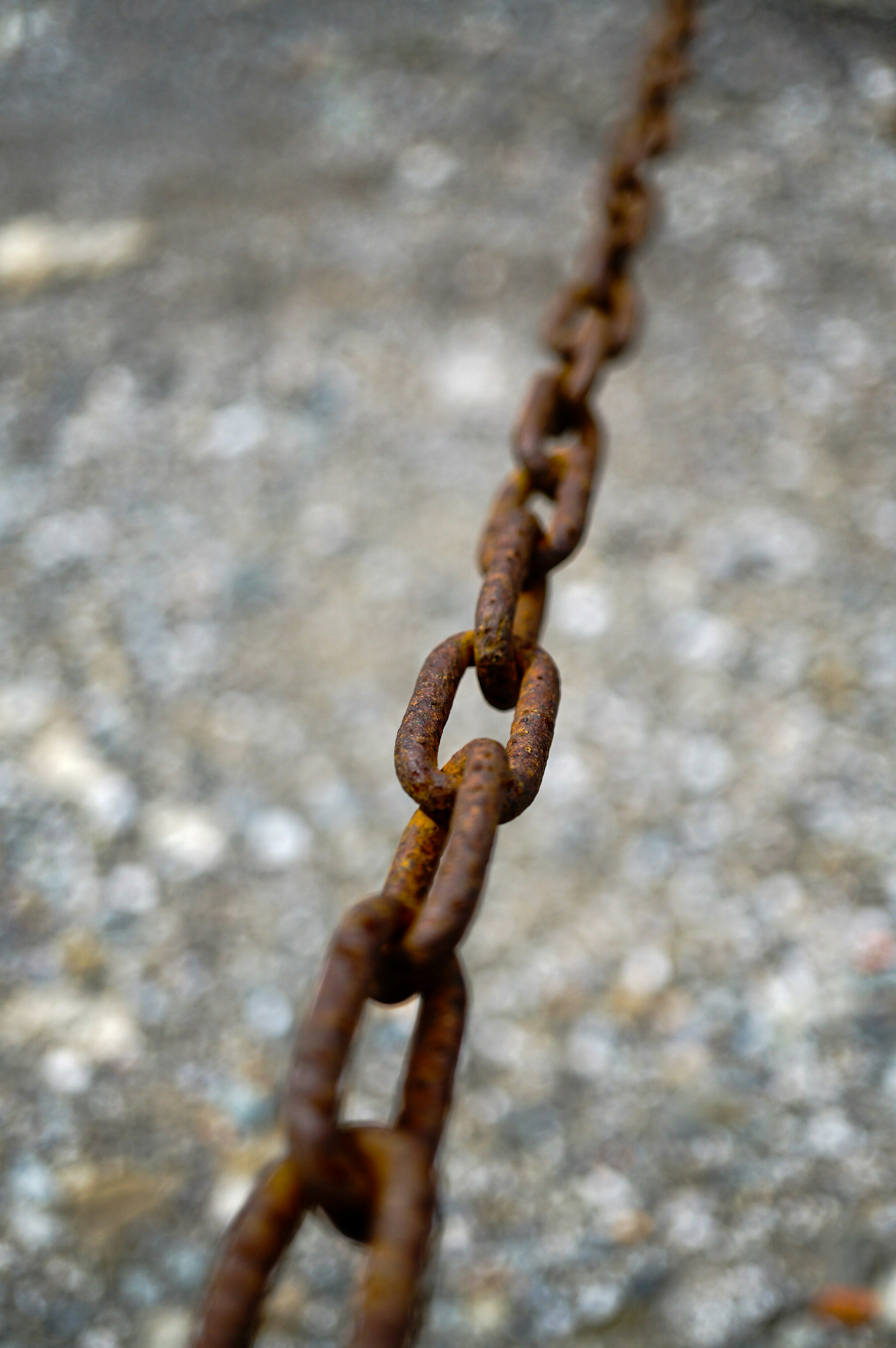 Rusty metal chain extending along the ground