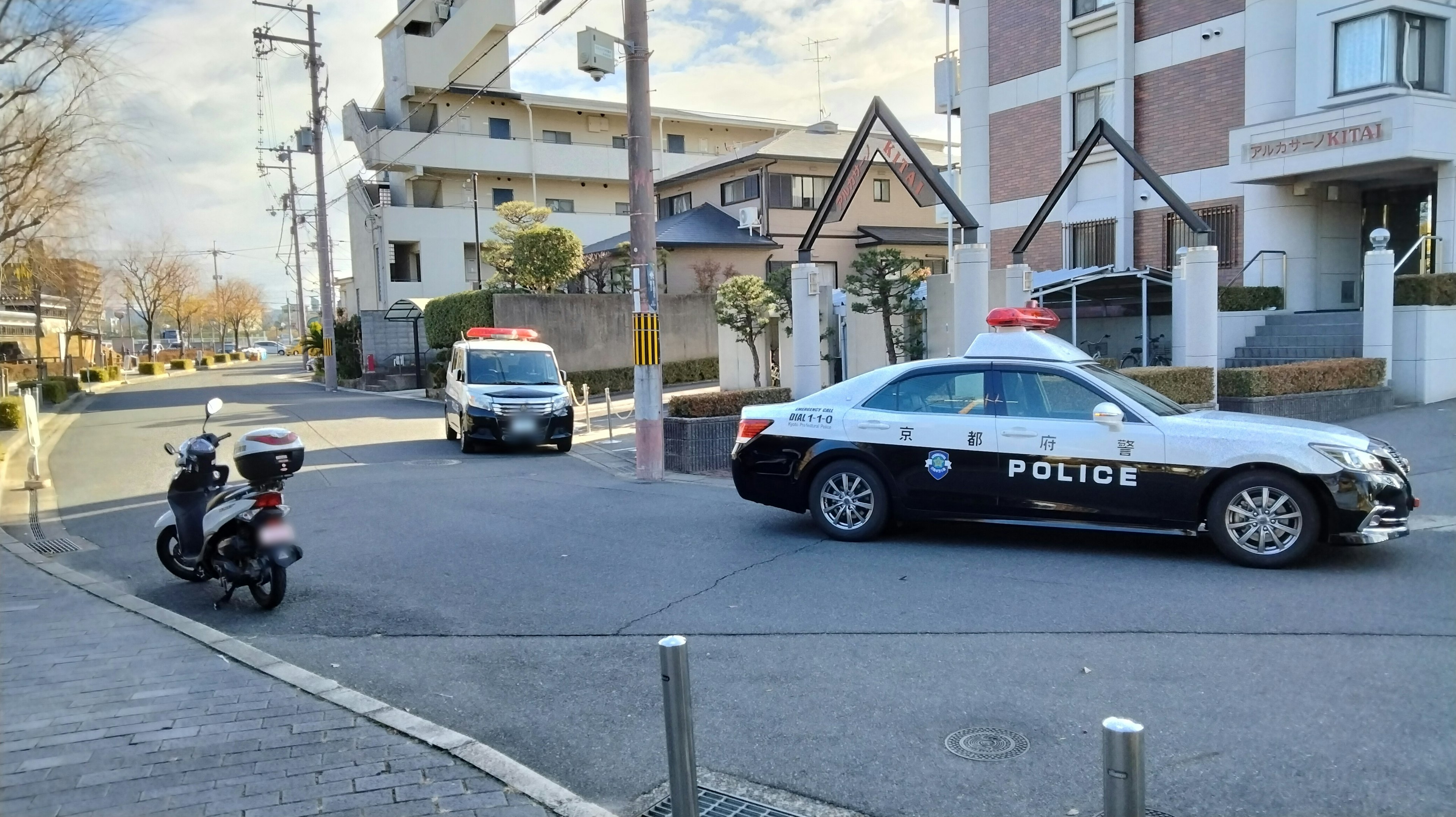 Police vehicles stopped at an intersection in a Japanese urban setting