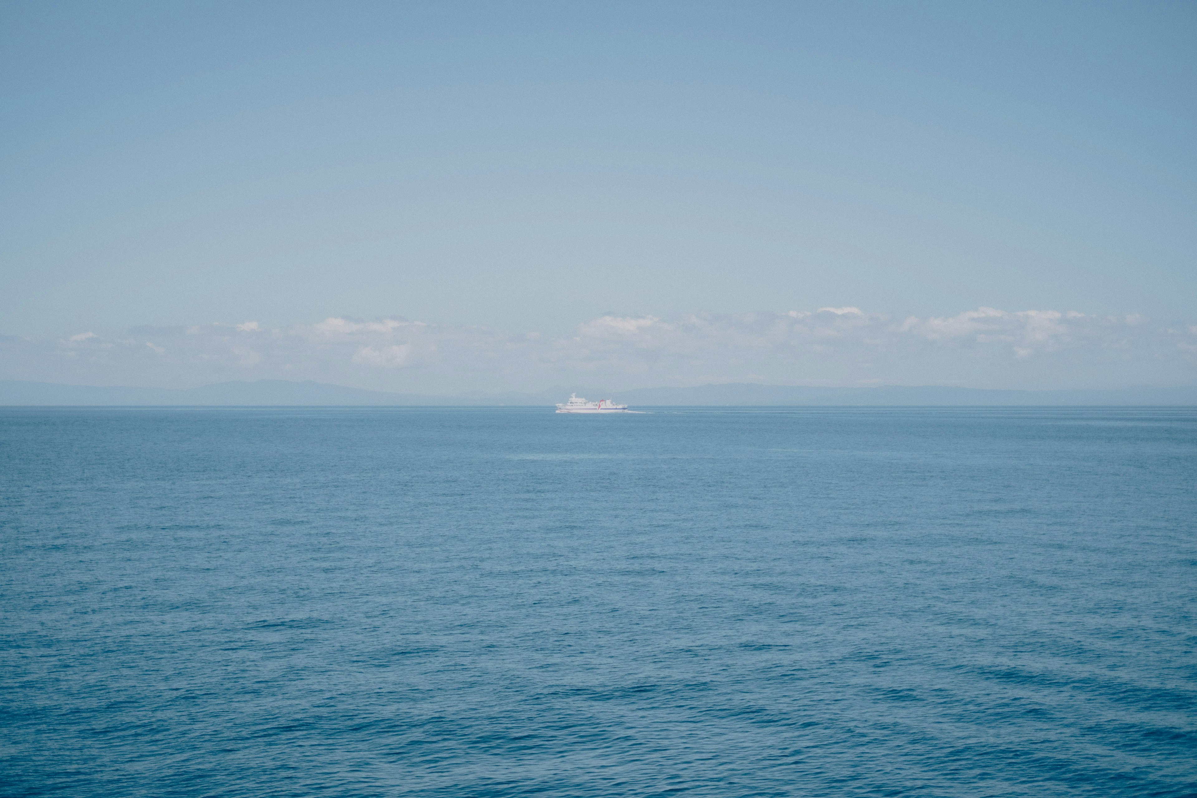 Vue panoramique de l'océan bleu et du ciel avec un navire au loin