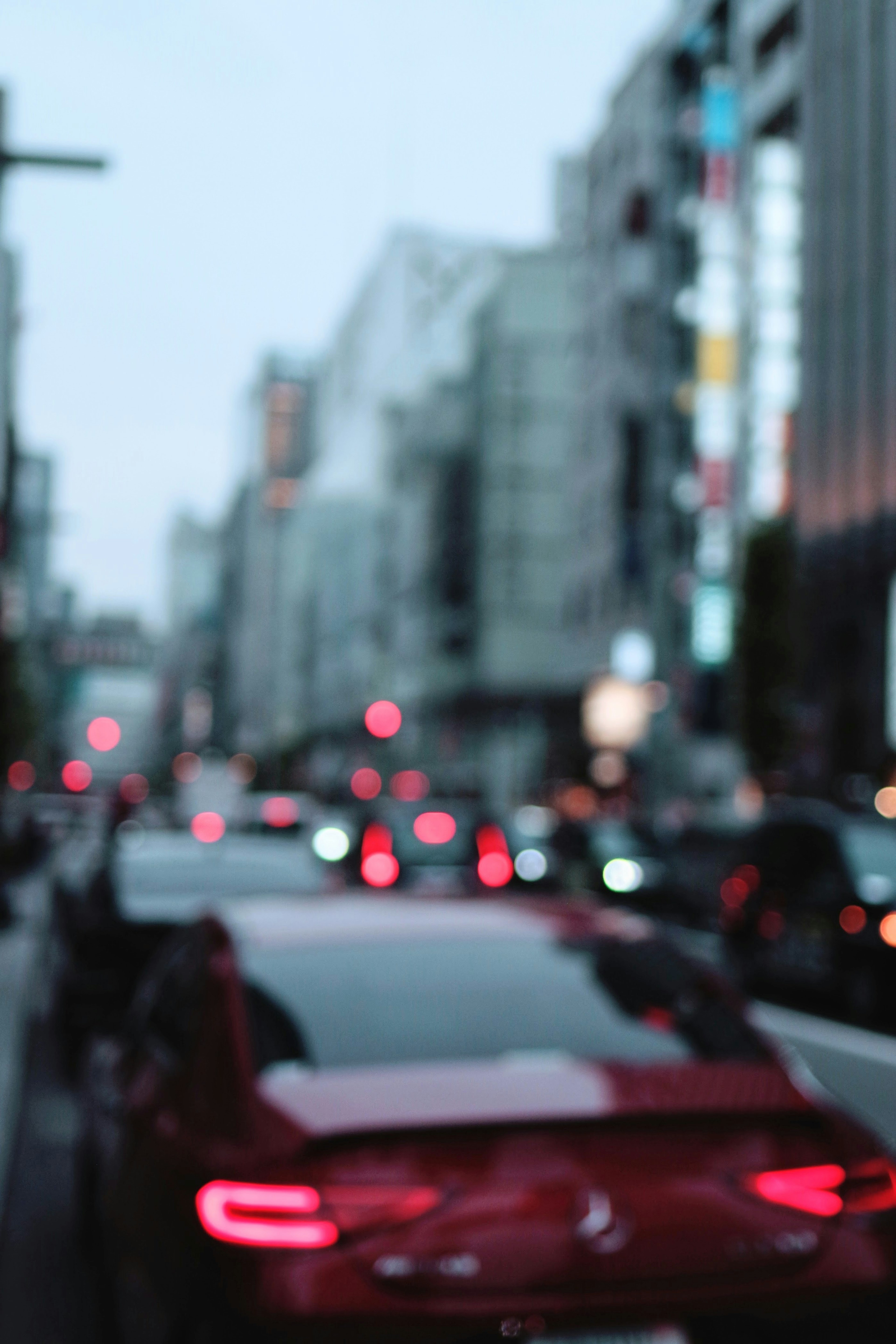 Immagine sfocata di un'auto rossa e di un paesaggio urbano al crepuscolo