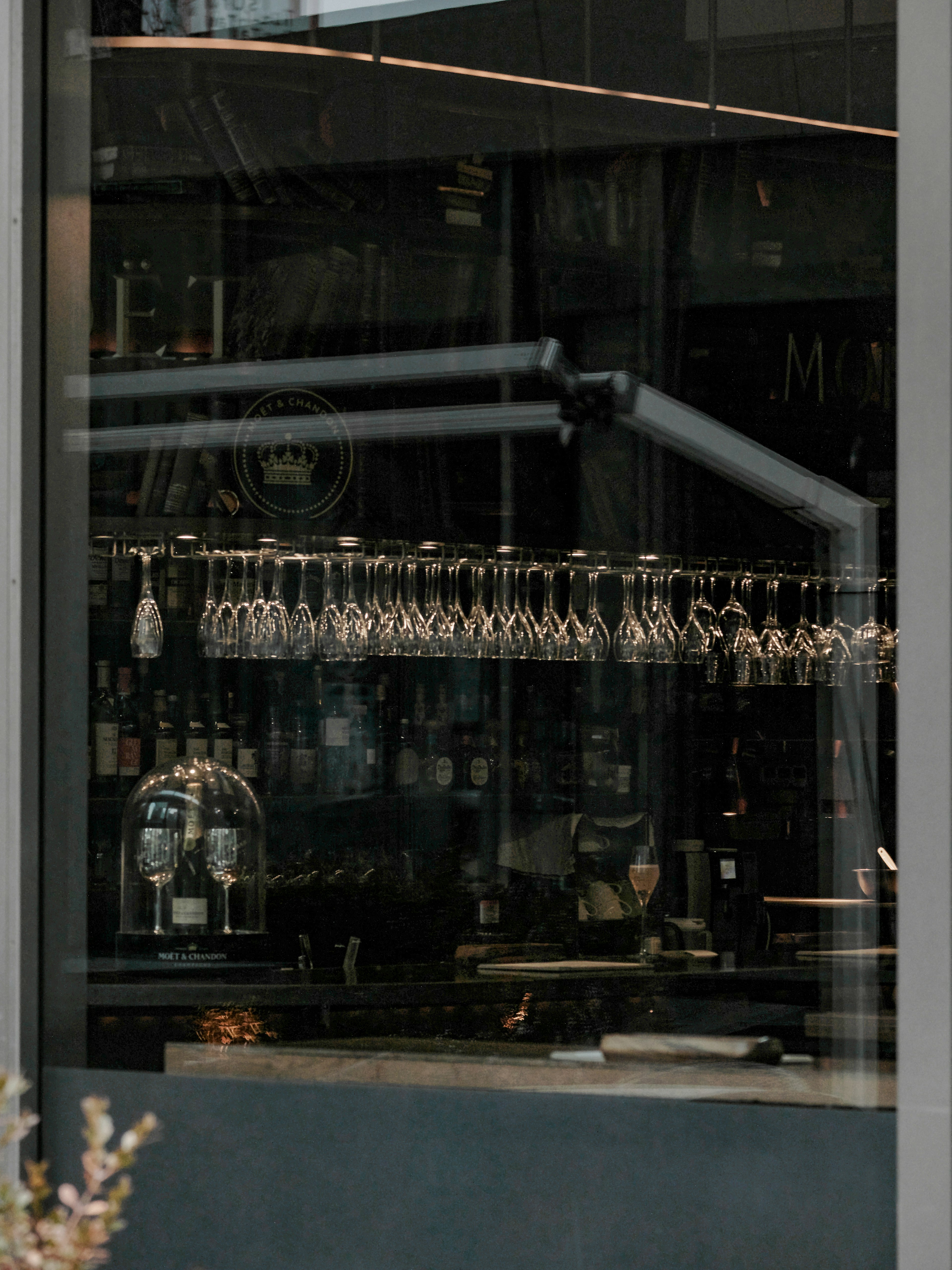 Vue d'un intérieur de bar sophistiqué à travers une fenêtre avec des verres alignés sur le comptoir