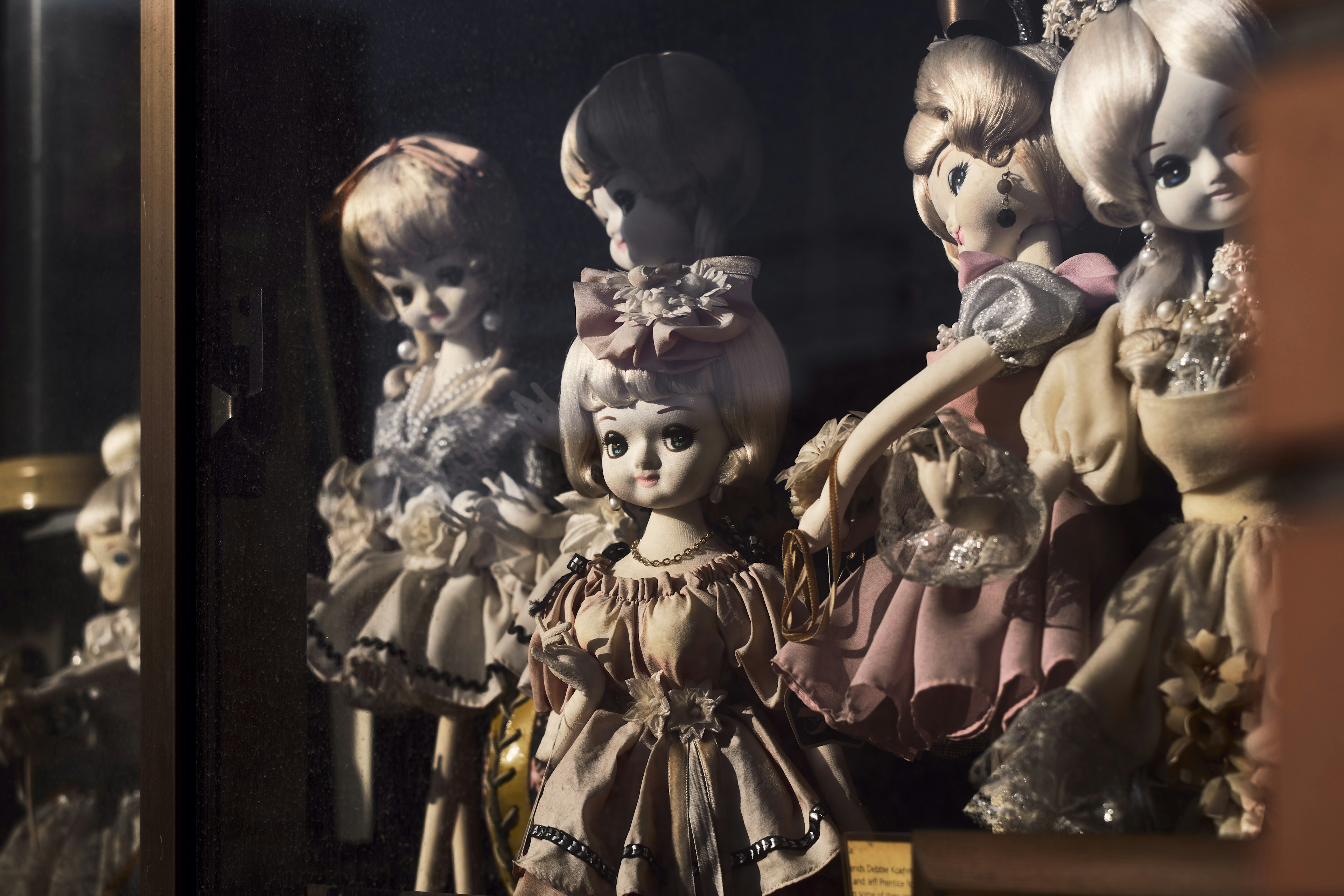 Photo de poupées vintage exposées dans une vitrine montrant divers vêtements et caractéristiques