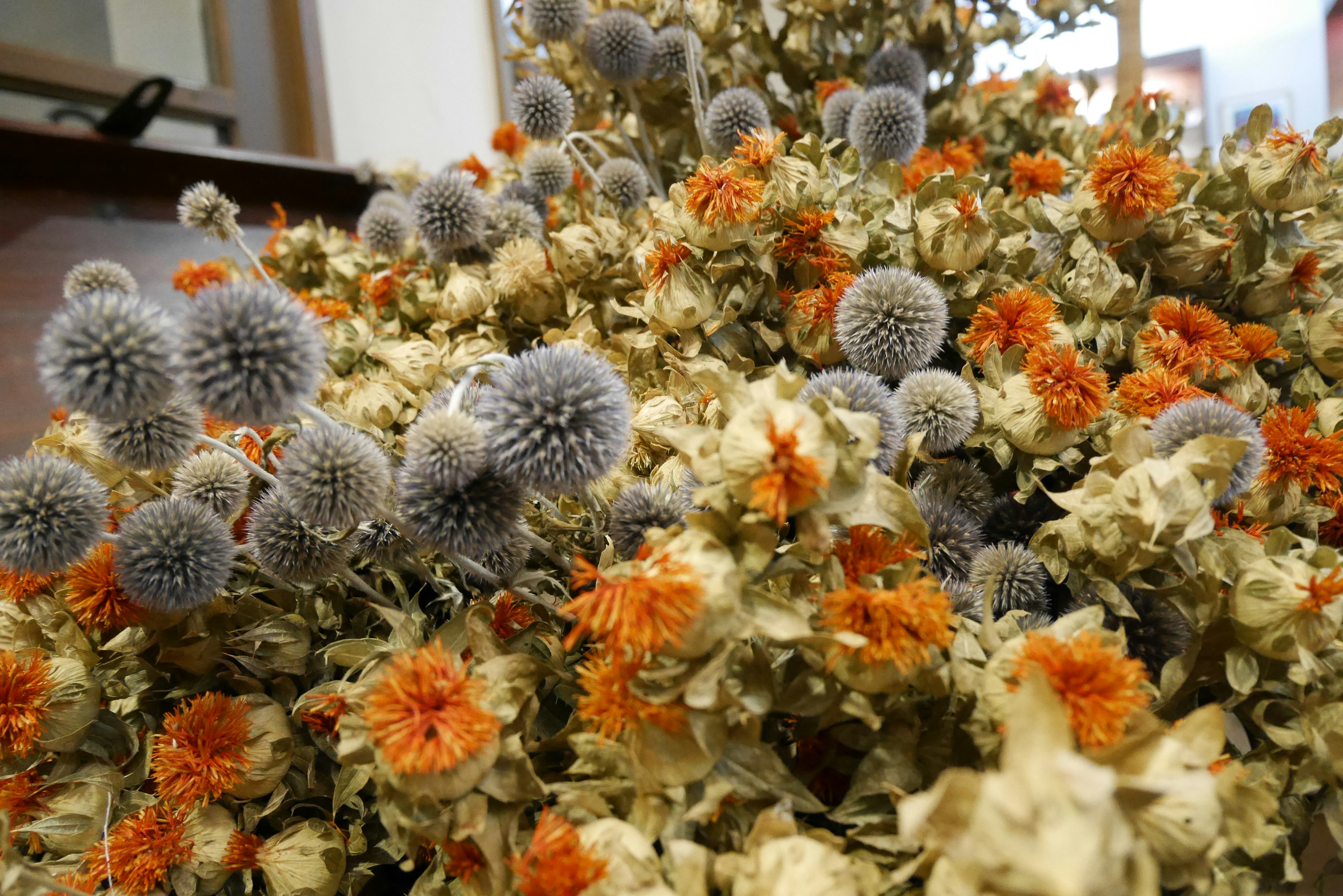 Un arreglo de flores secas con elementos naranjas y grises