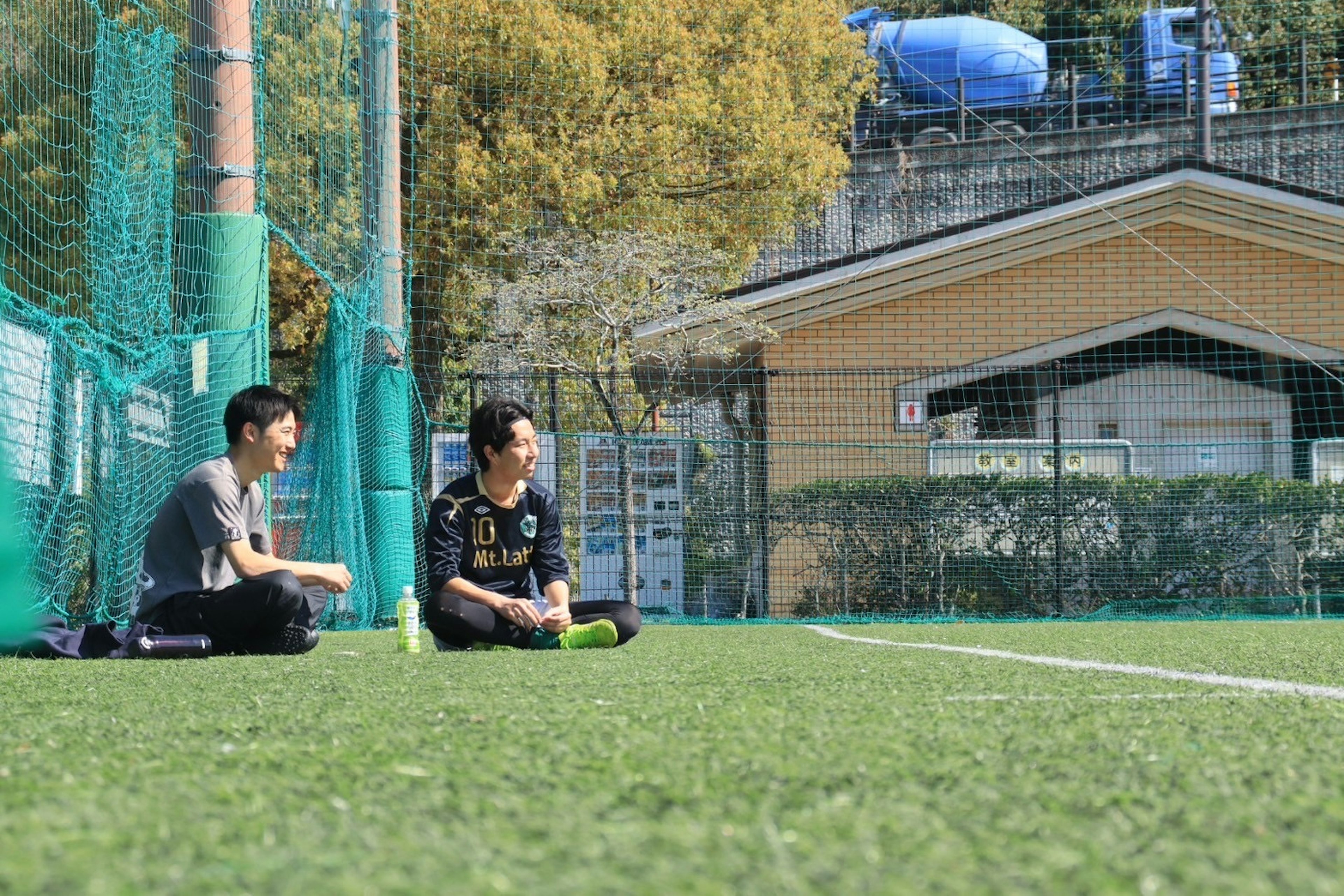 Deux hommes assis sur du gazon artificiel sur un terrain de soccer